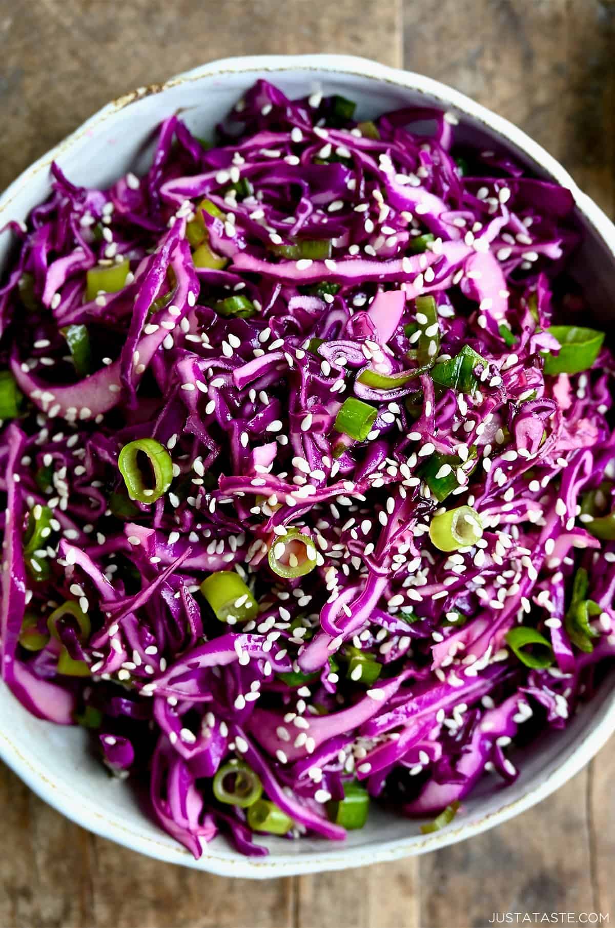 Asian slaw made with shredded purple cabbage, fresh lime juice, fish sauce and sesame oil in a large white serving bowl.