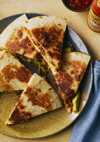 Homemade quesadilla cut into five triangles on a plate.