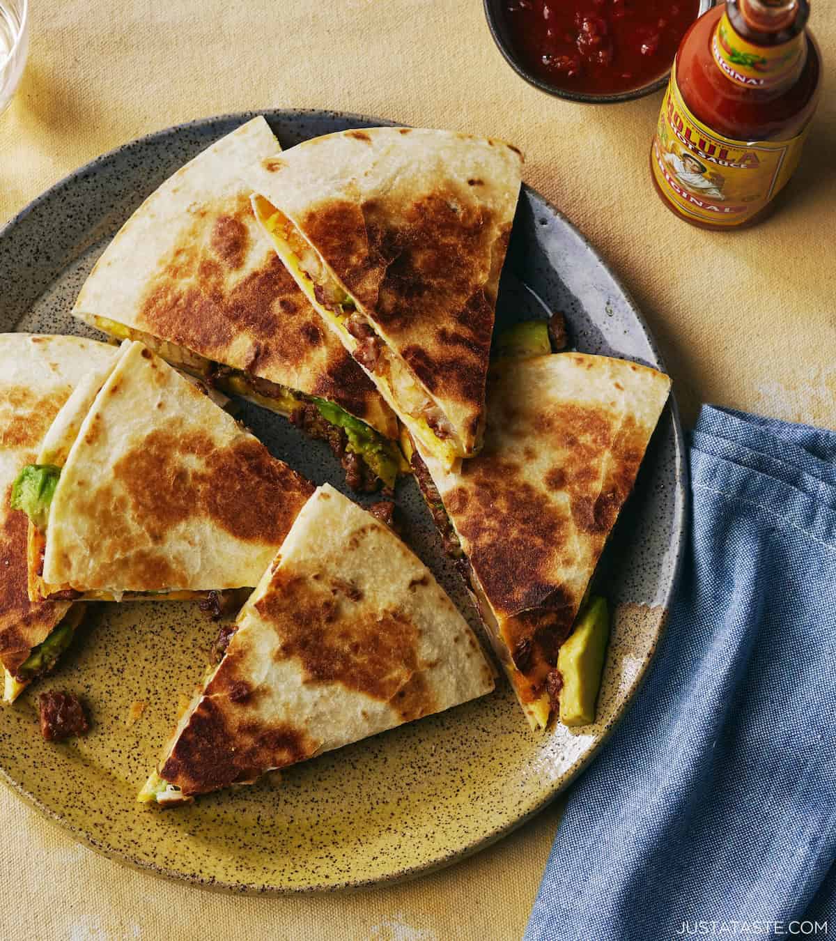 Sliced quesadilla on a plate, with golden, crispy tortillas and sausage oozing from the center.