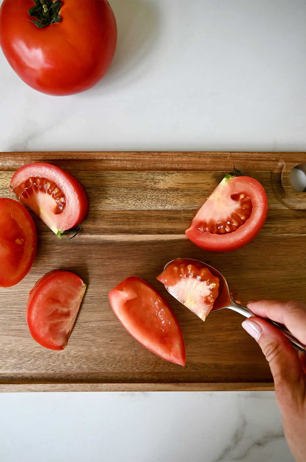Coring and scooping out the seeds from a Roma tomato.