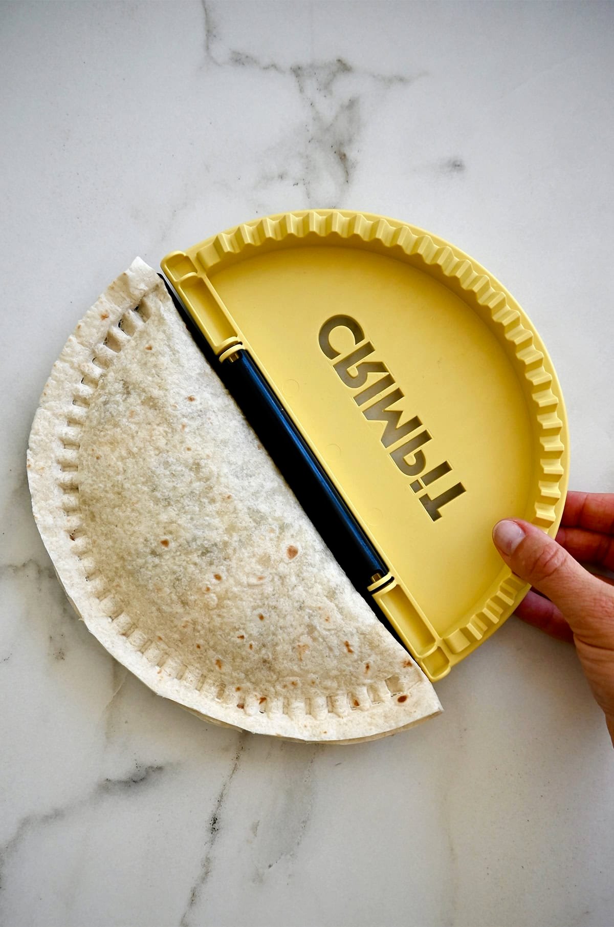 A filled tortilla folded in half and sealed using the CRIMPiT Tortilla Sealer.