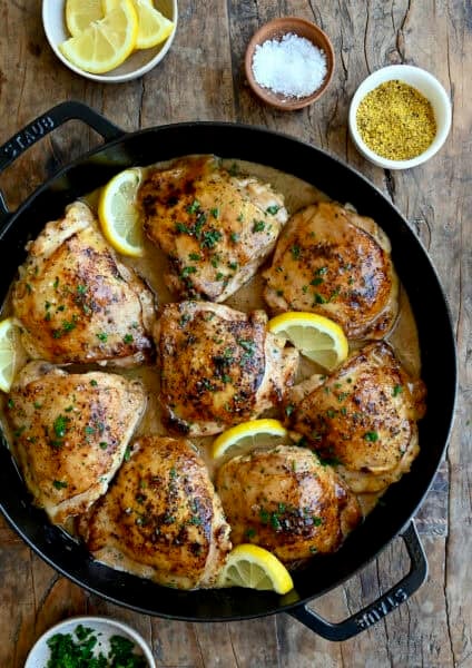 Easy lemon pepper chicken in a cast iron skillet with slices of lemon.