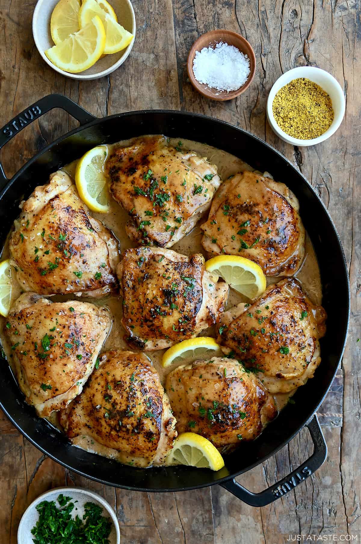 Easy lemon pepper chicken in a cast iron skillet with slices of lemon.