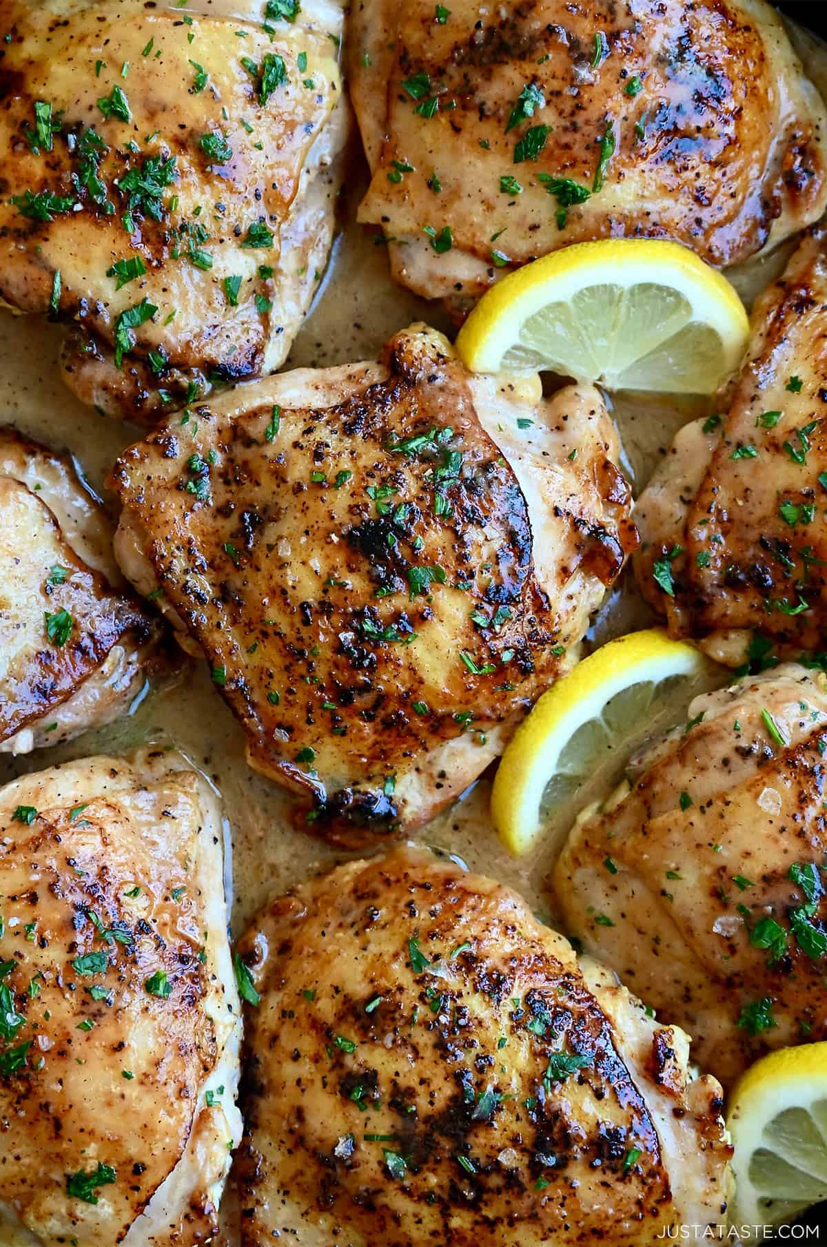 Pan-seared chicken thighs in a lemon pepper pan sauce with slices of lemon.
