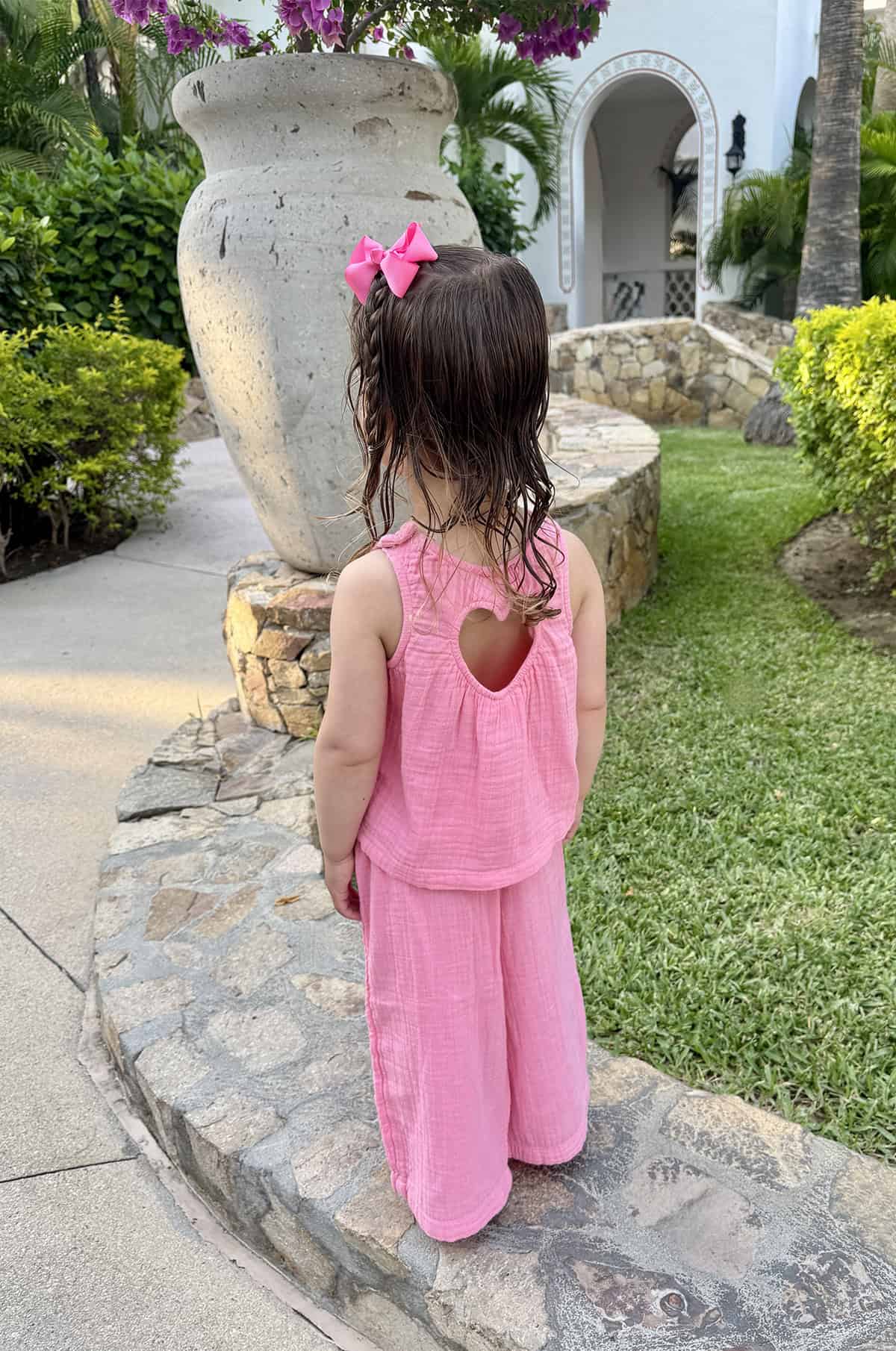 The back of a little girl's head with a pink bow and braid