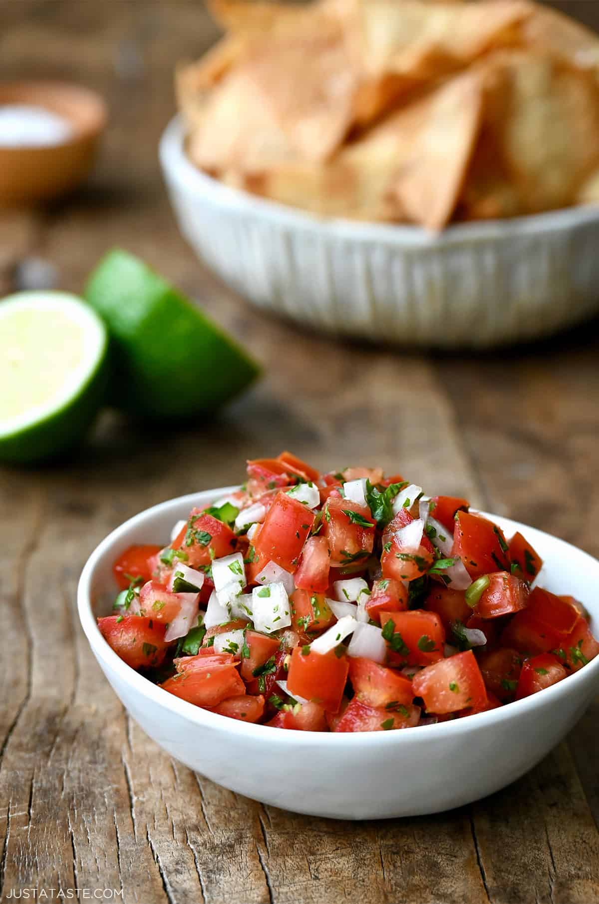 Fresh homemade pico de gallo in a small bowl near another bowl filled with tortilla chips.
