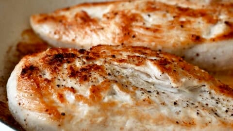 Seared chicken breasts in a large skillet.