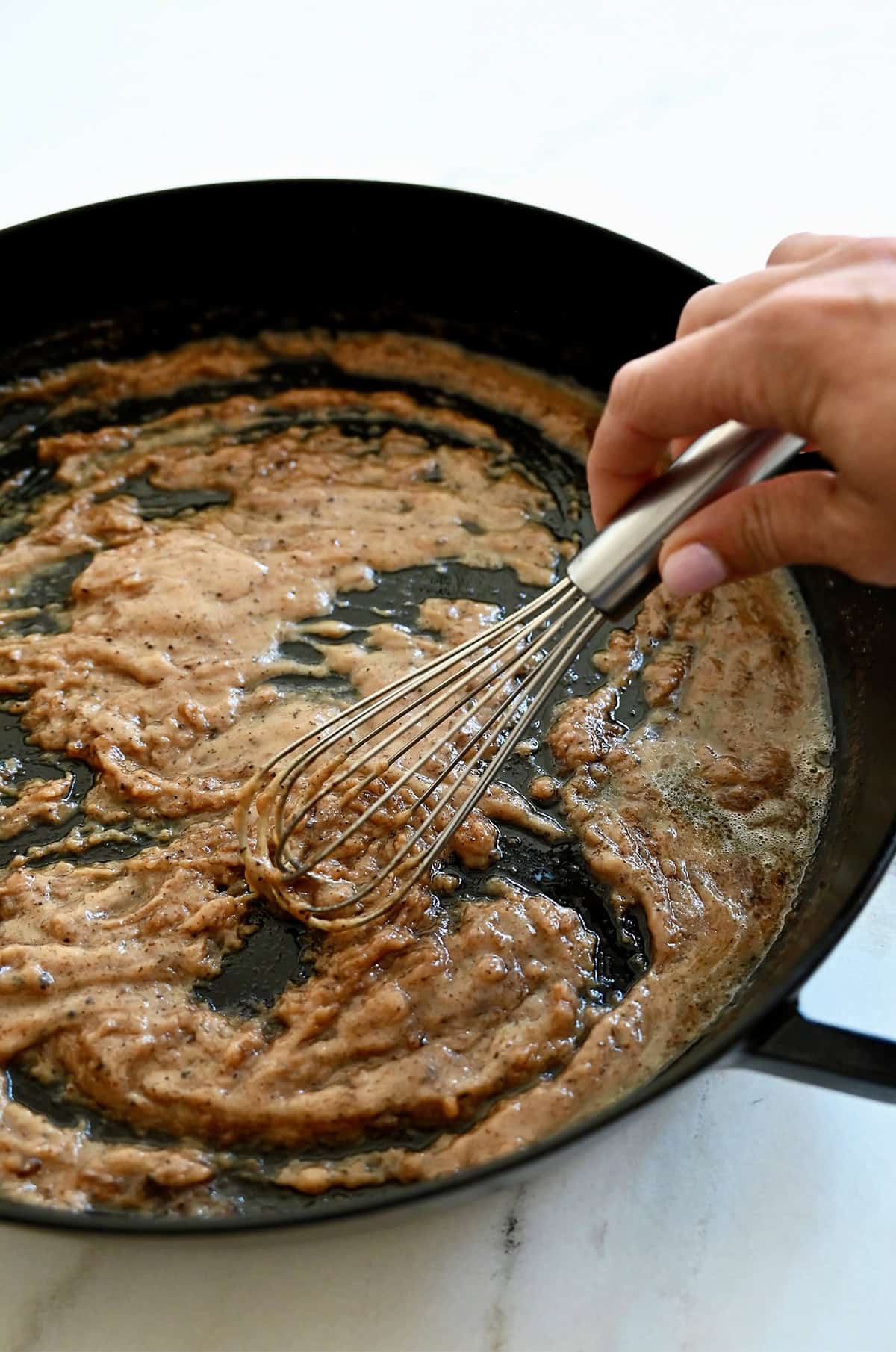 A roux made of equal parts fat and flour starts to form in a skillet.