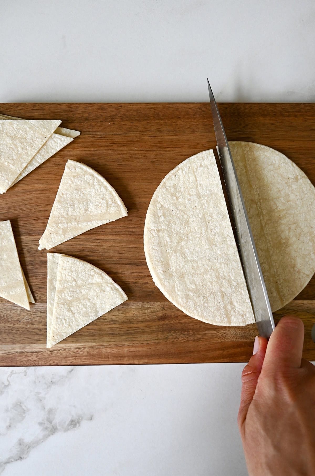 Cutting corn tortillas into wedges with a sharp knife.