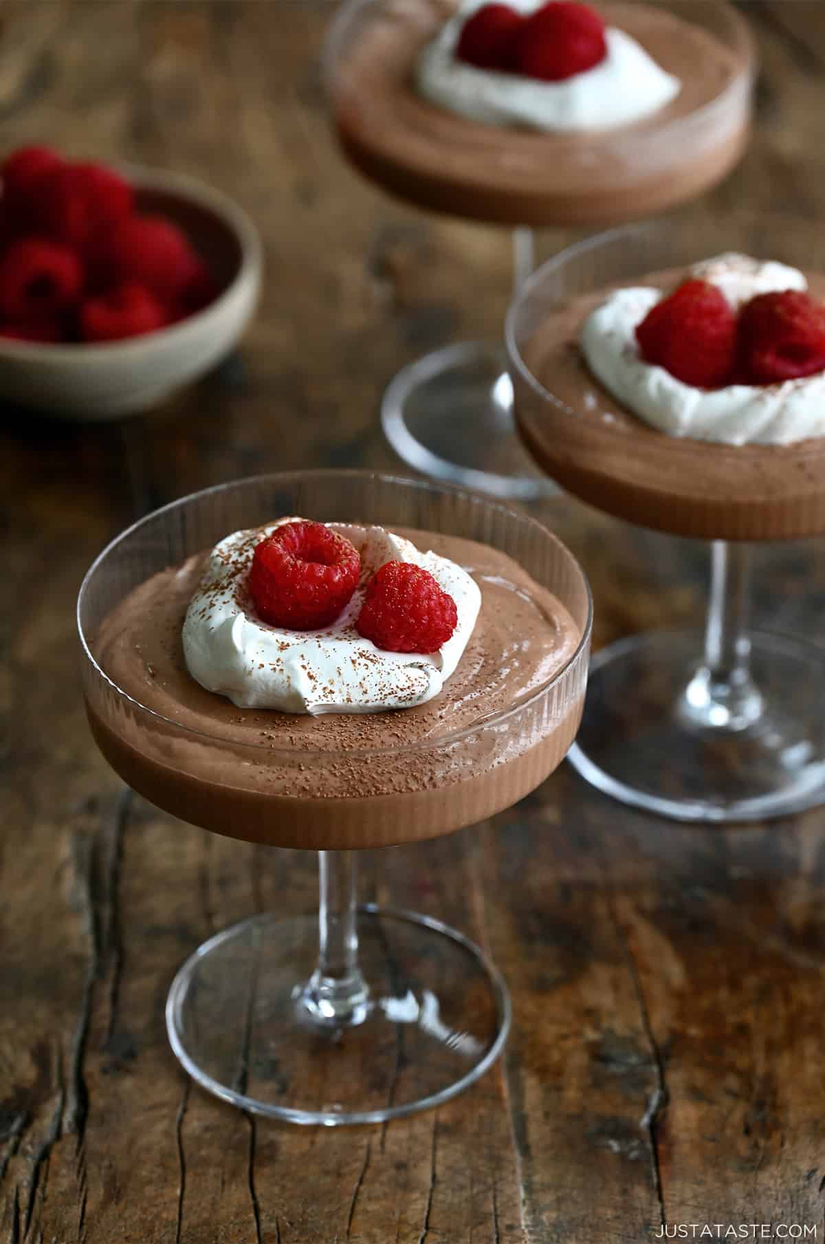 Clear glasses containing Cottage Cheese Chocolate Mousse topped with whipped cream and raspberries
