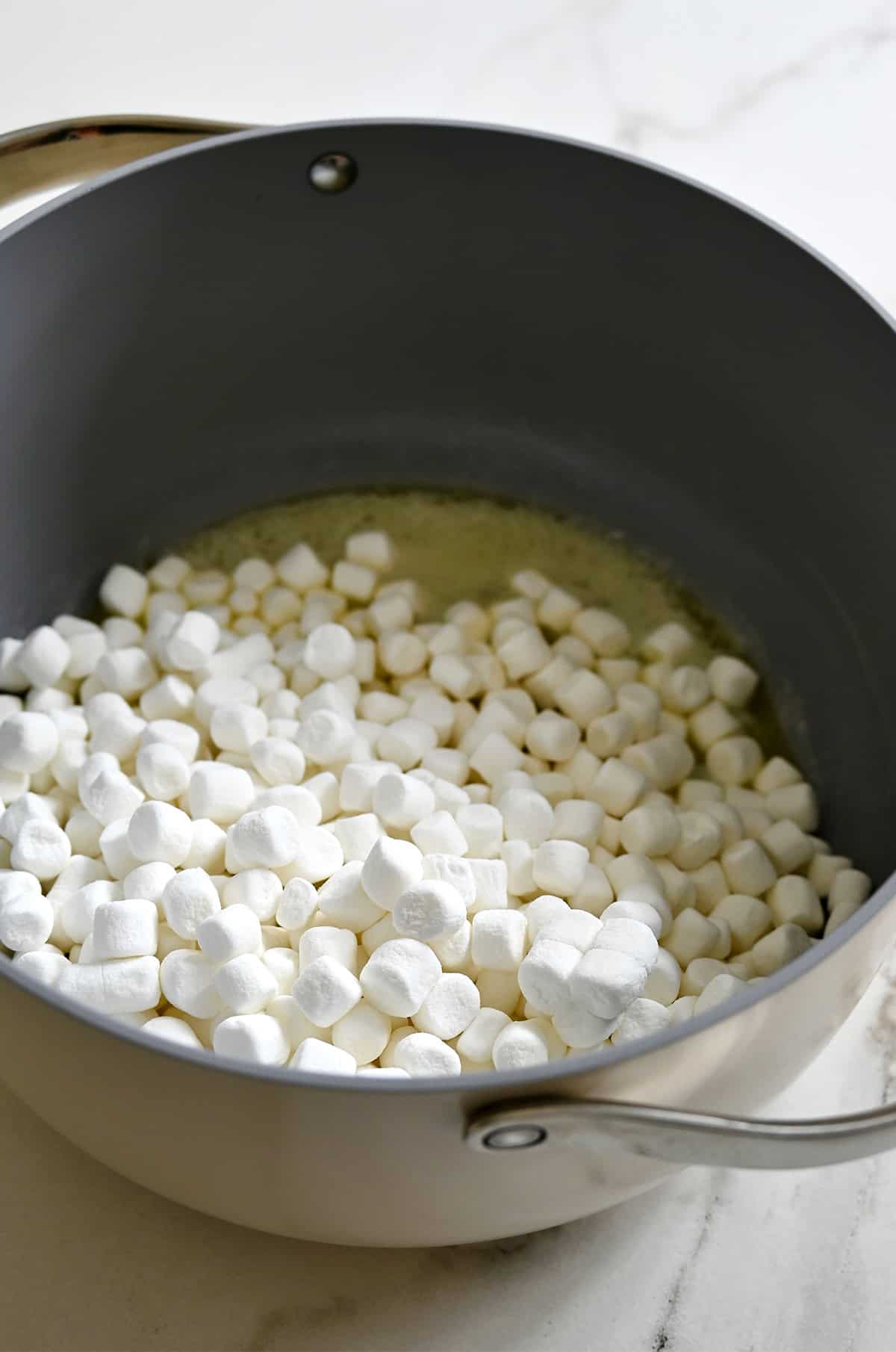 Melting butter and mini marshmallows in a large stockpot.