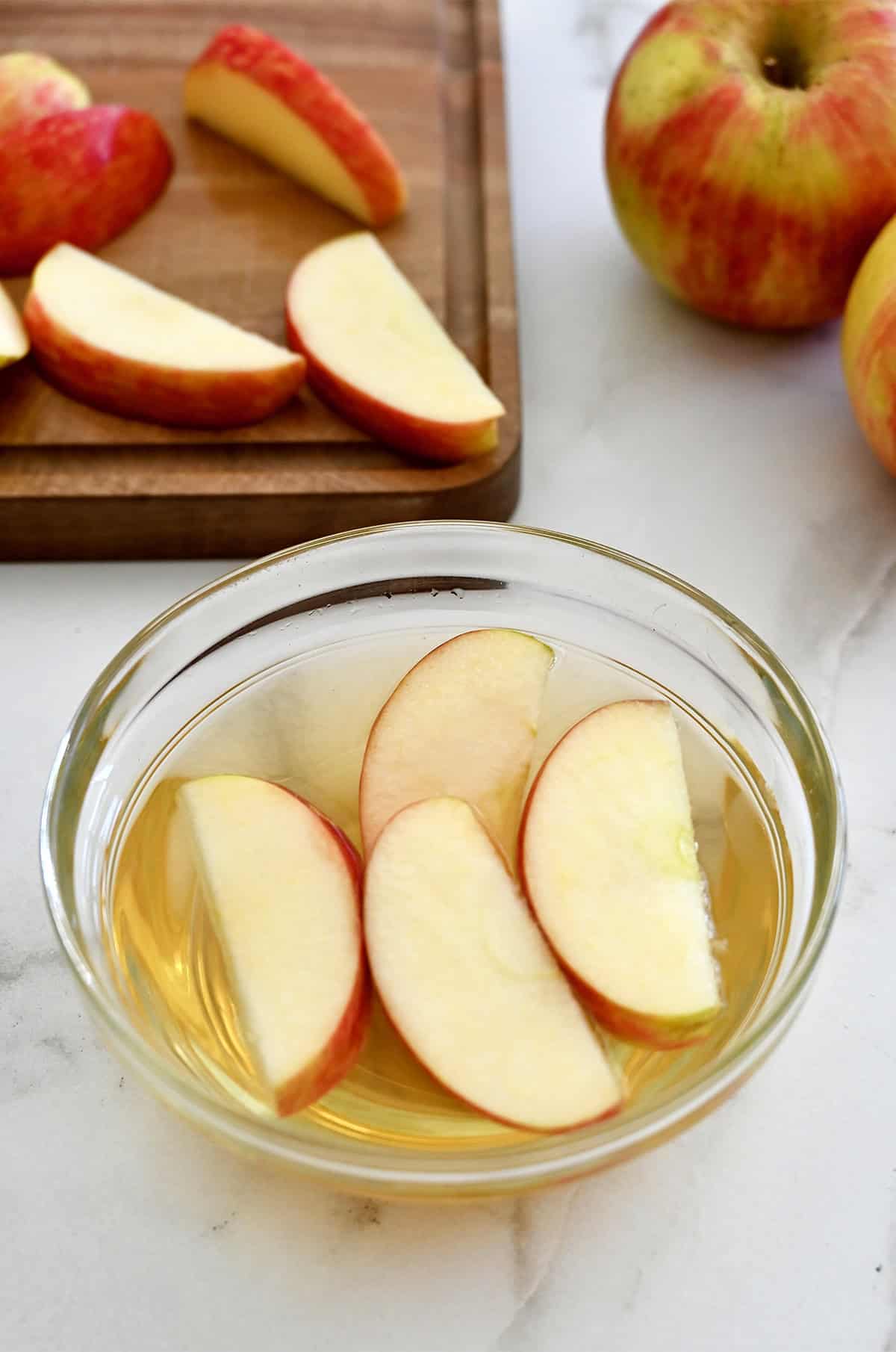 A small bowl containing apple slices soaking in apple cider vinegar.
