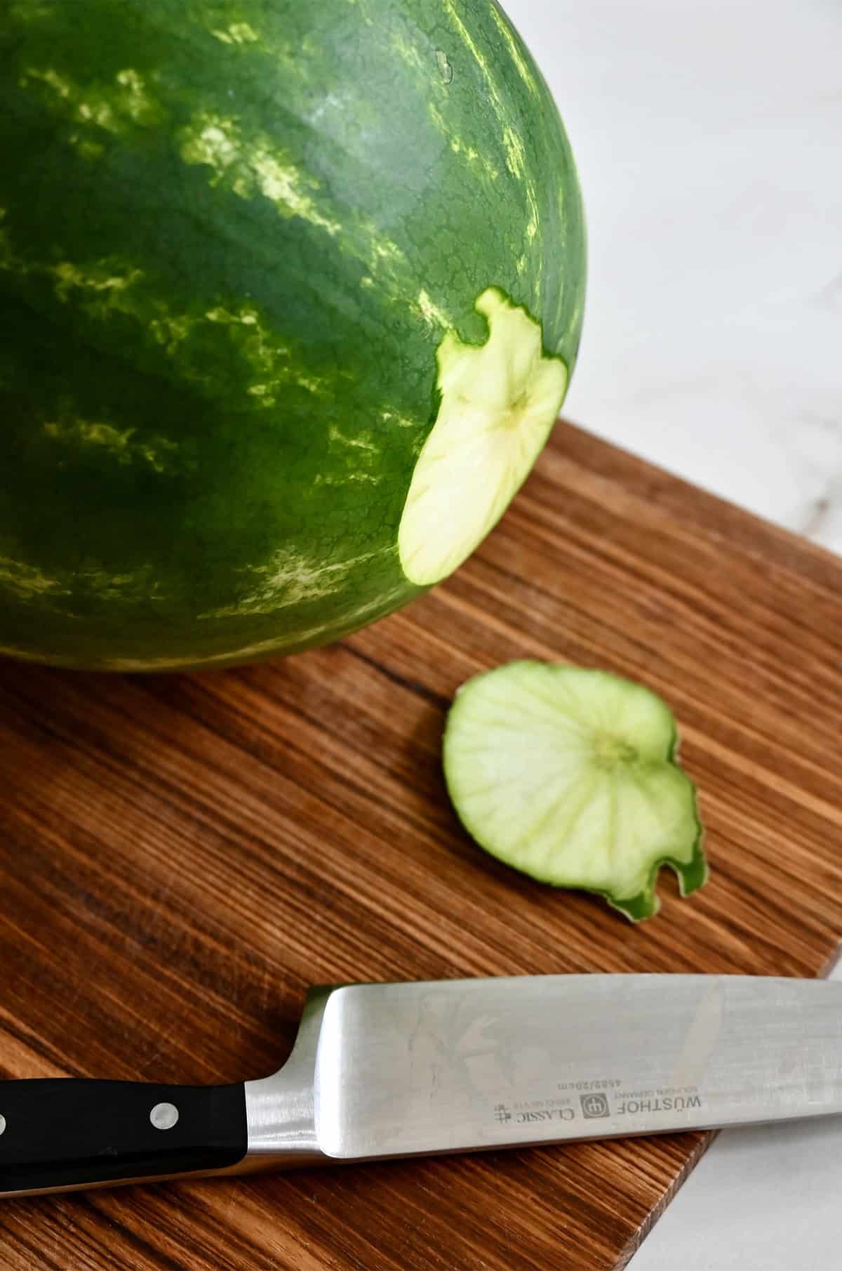 Slicing the base of a watermelon off to make it sit level.