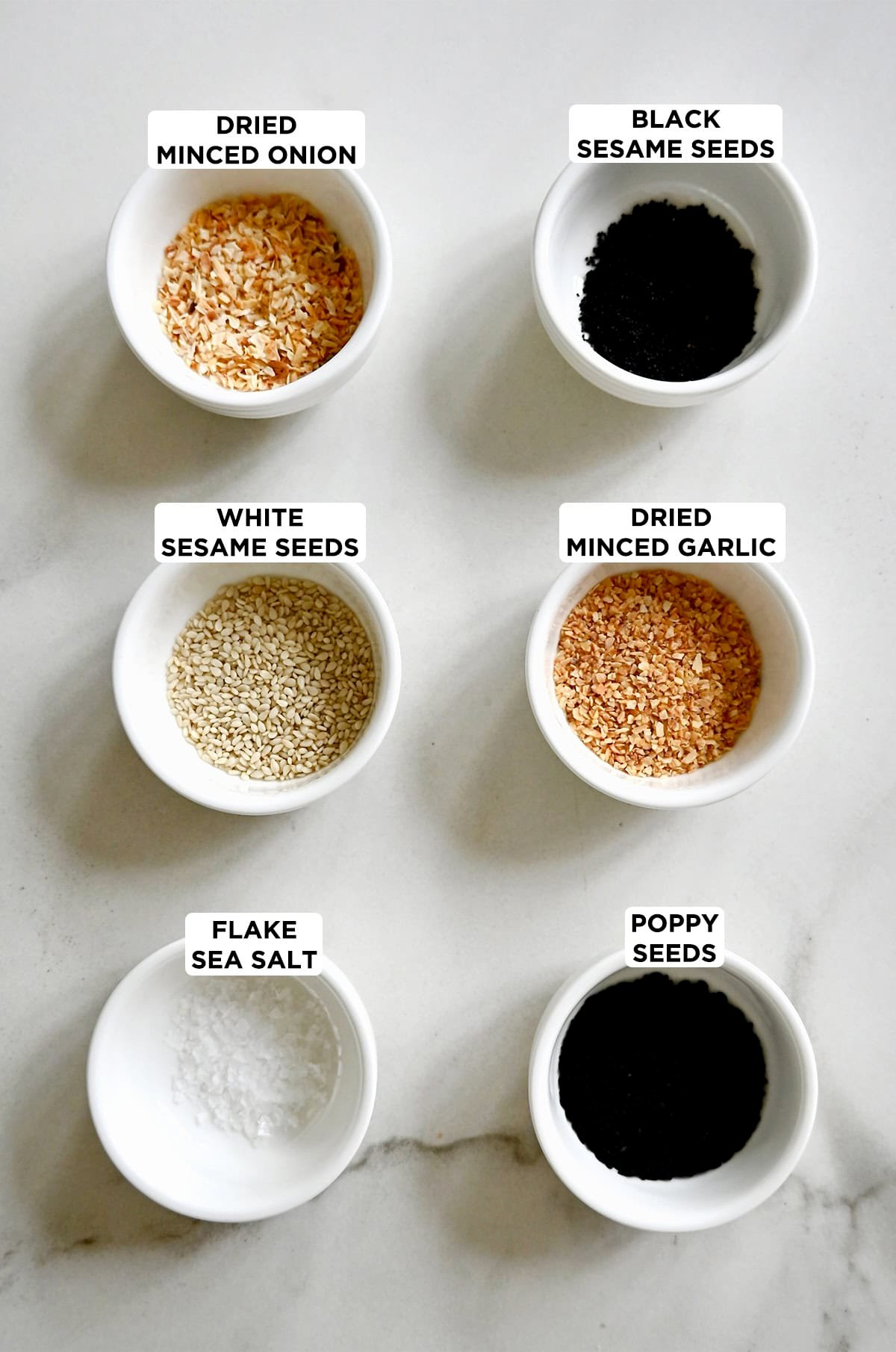 The six ingredients to make everything bagel seasoning: white sesame seeds, black sesame seeds, dried minced garlic, dried minced onion, poppy seeds and flaky sea salt.