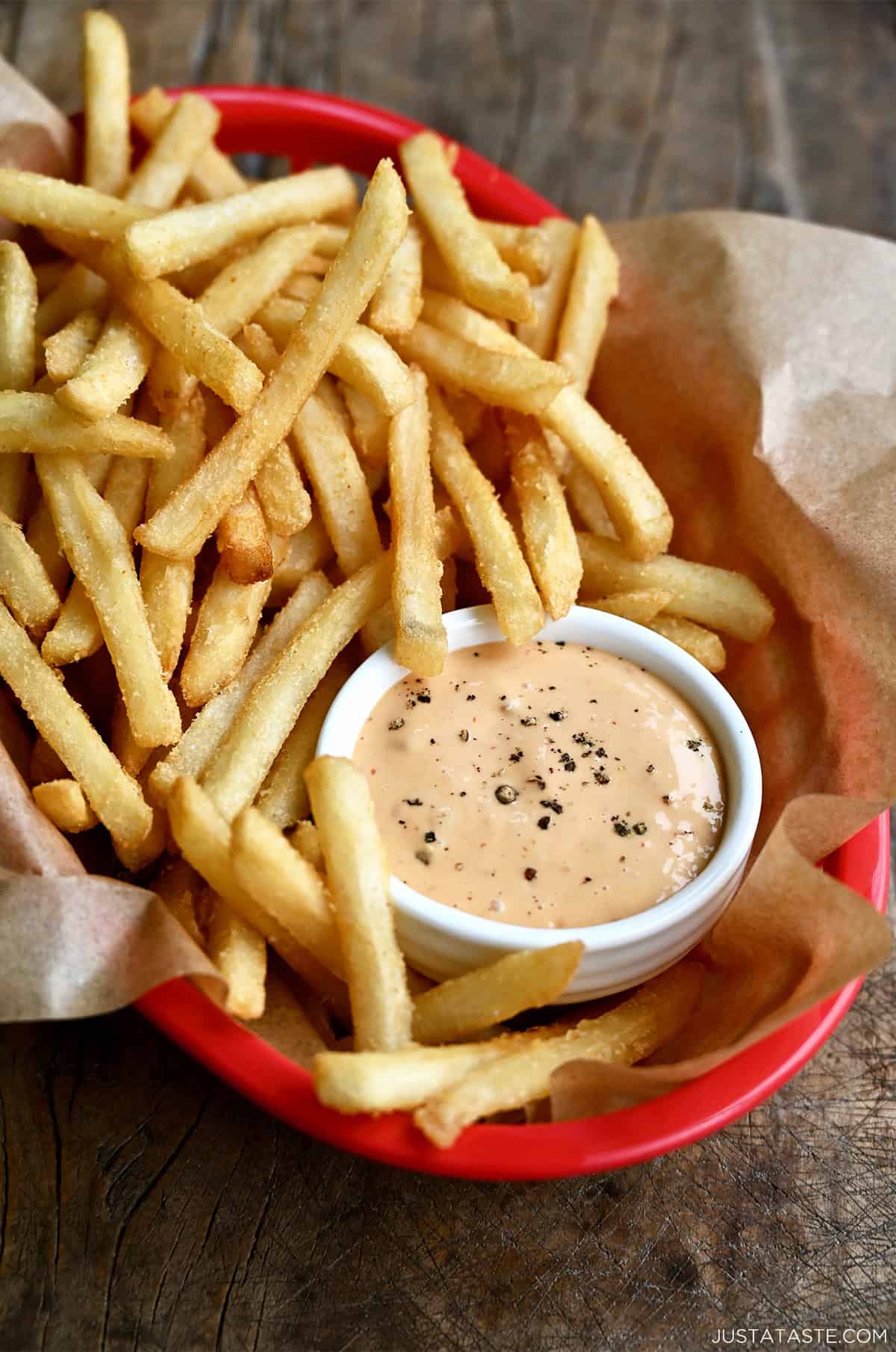 Homemade burger sauce in a small bowl in a red food basket with French fries.