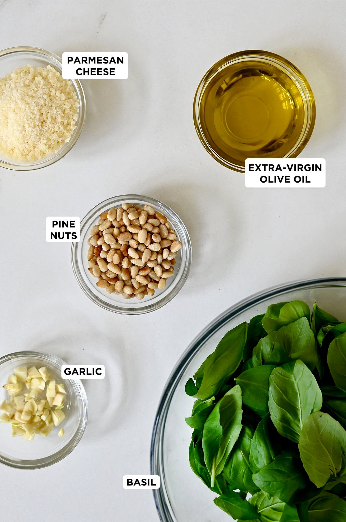 The five ingredients needed to make basil pesto: fresh basil leaves, garlic, pine nuts, Parmesan cheese and extra-virgin olive oil.
