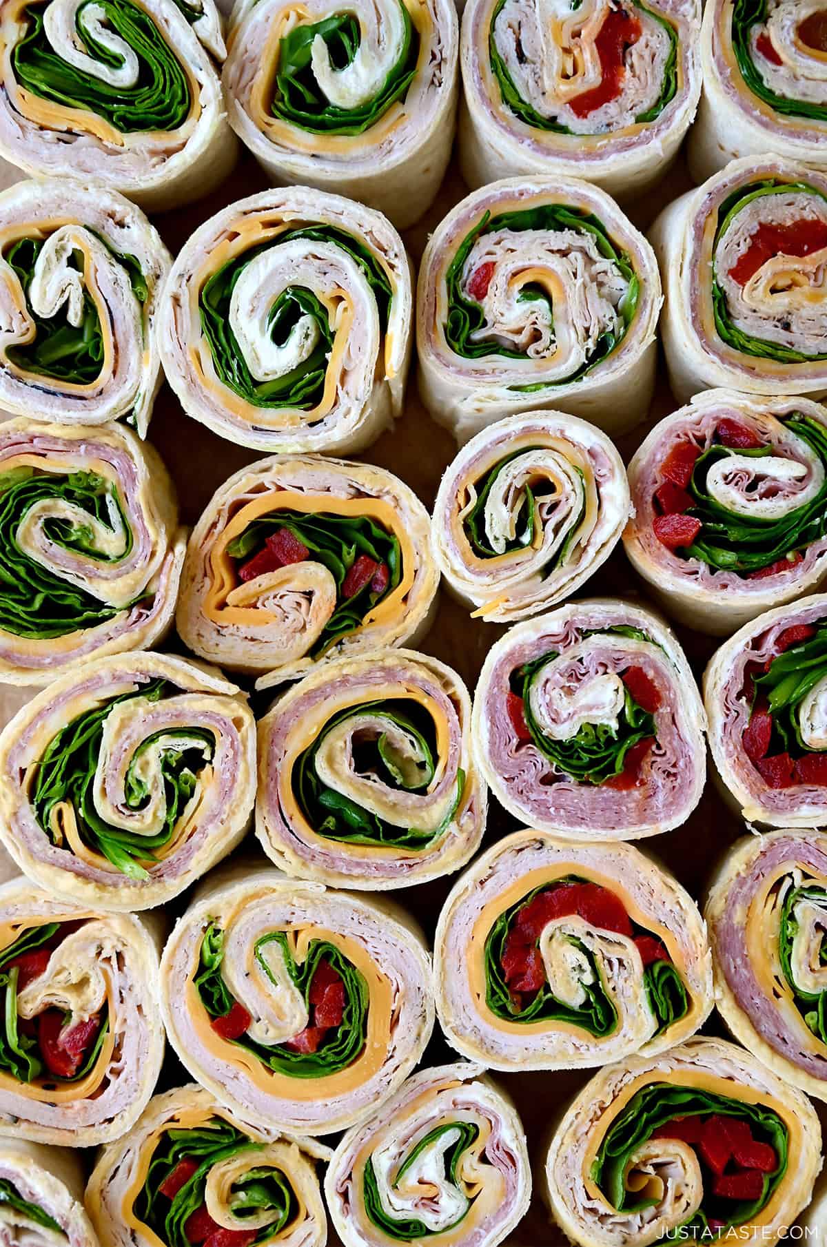 Several different flavors of pinwheel sandwiches, including ham and cheese pinwheels, turkey and spinach pinwheels, and salami pinwheel sandwiches.