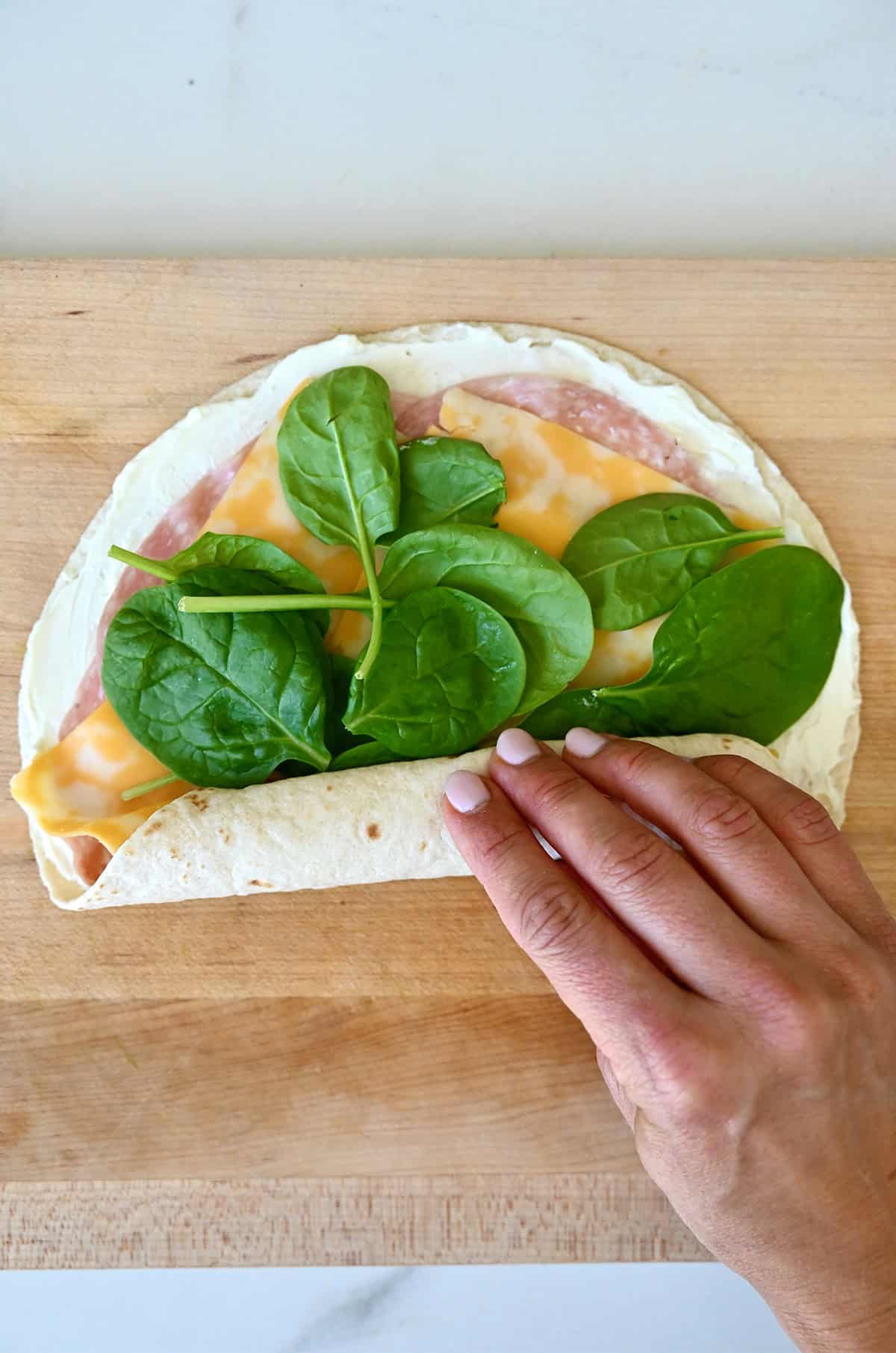 Tightly rolling up a tortilla with sandwich fillings.