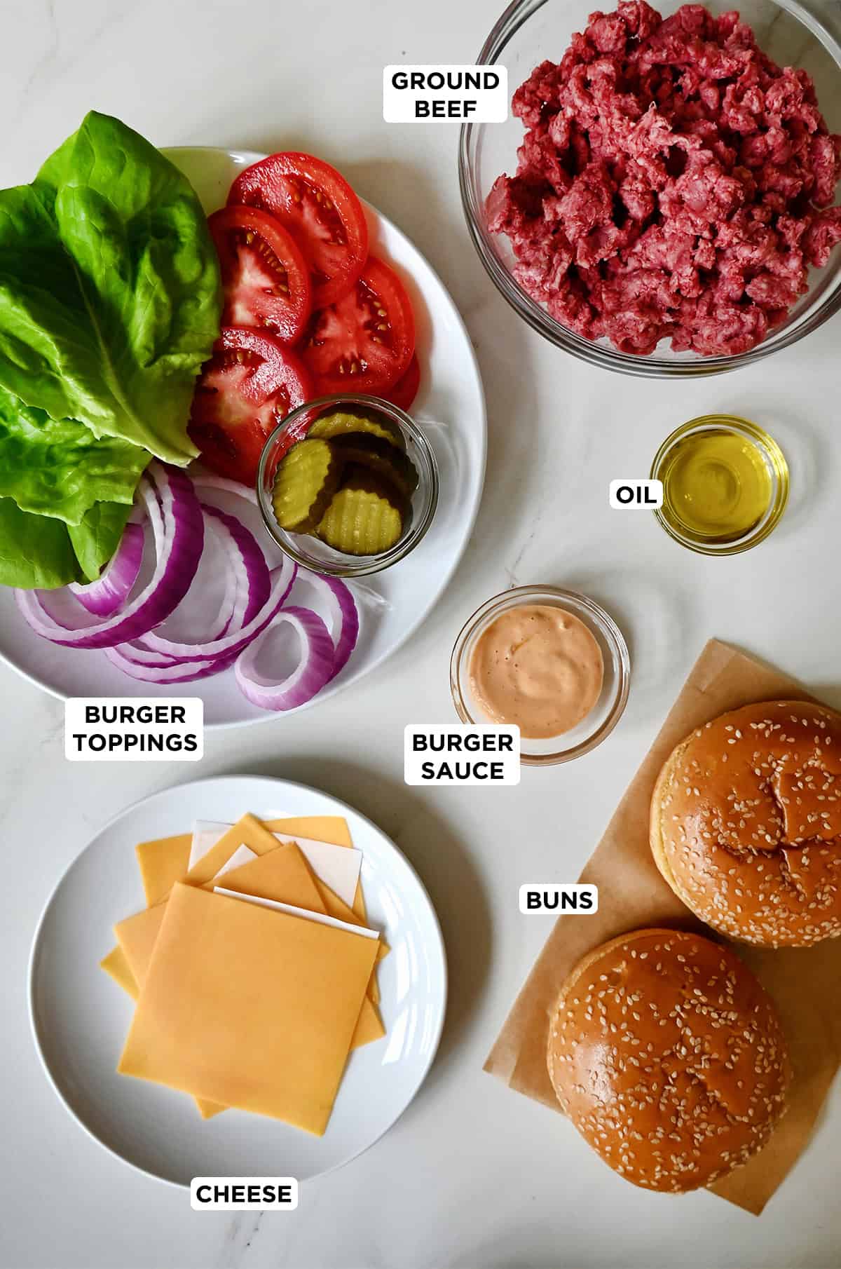 Ingredients to make a cheese smash burger, including ground beef, hamburger buns, slices of cheese, burger sauce and assorted classic burger toppings.