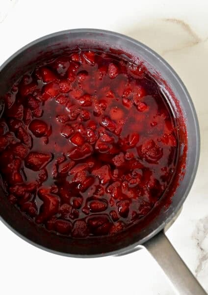 Homemade strawberry syrup in a saucepan.