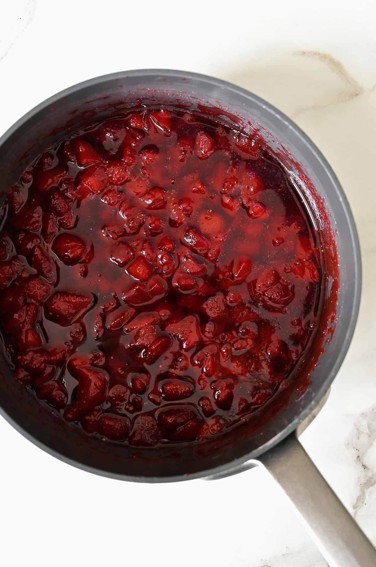 Homemade strawberry syrup in a saucepan.