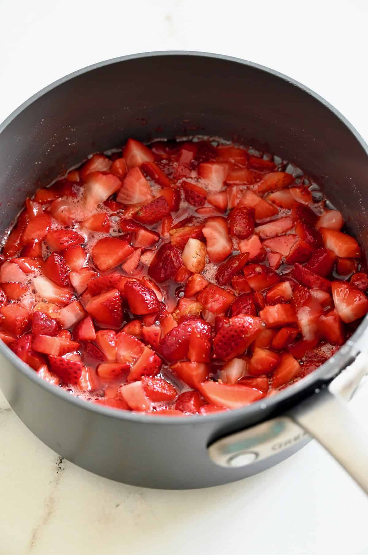 Diced strawberries simmering in a saucepan with sugar, lemon juice and lemon zest.