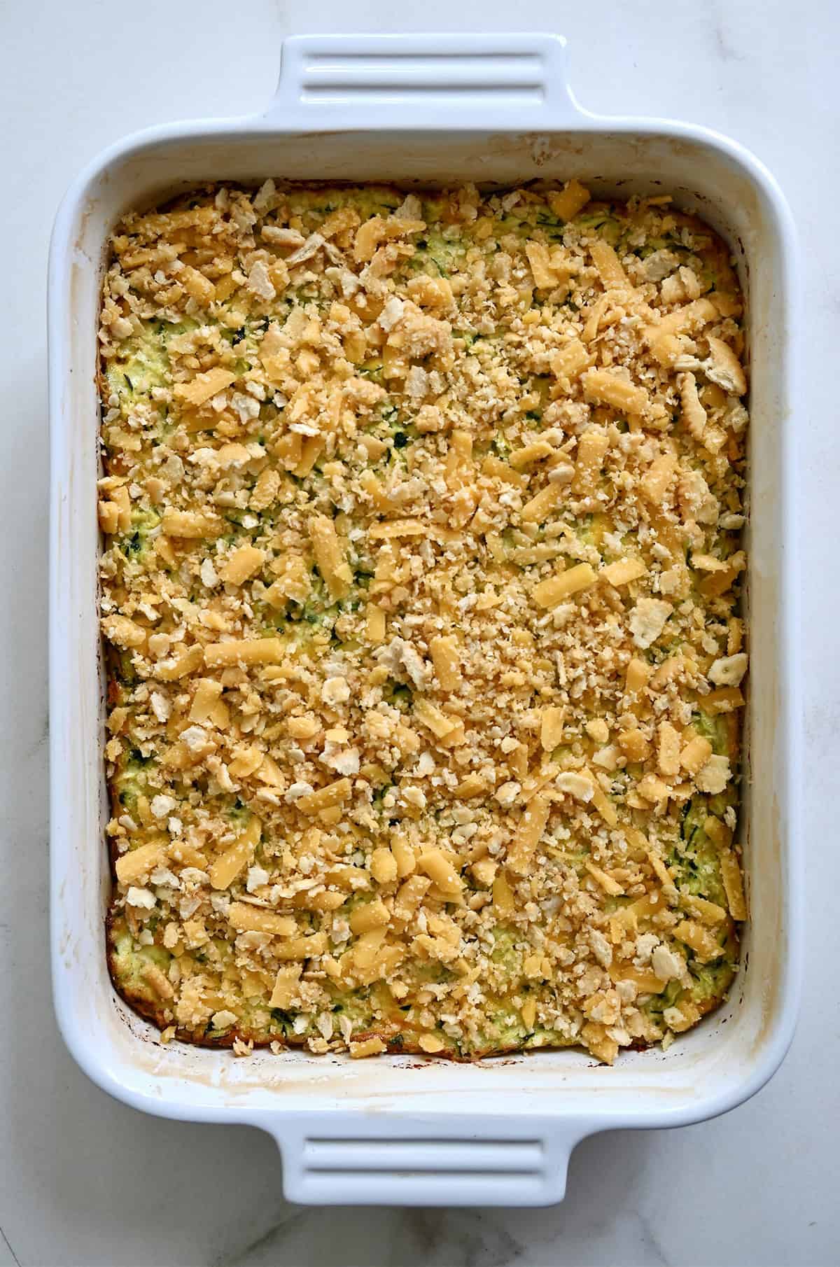 Untoasted cheese and cracker topping atop a casserole in a 9x13 baking dish.