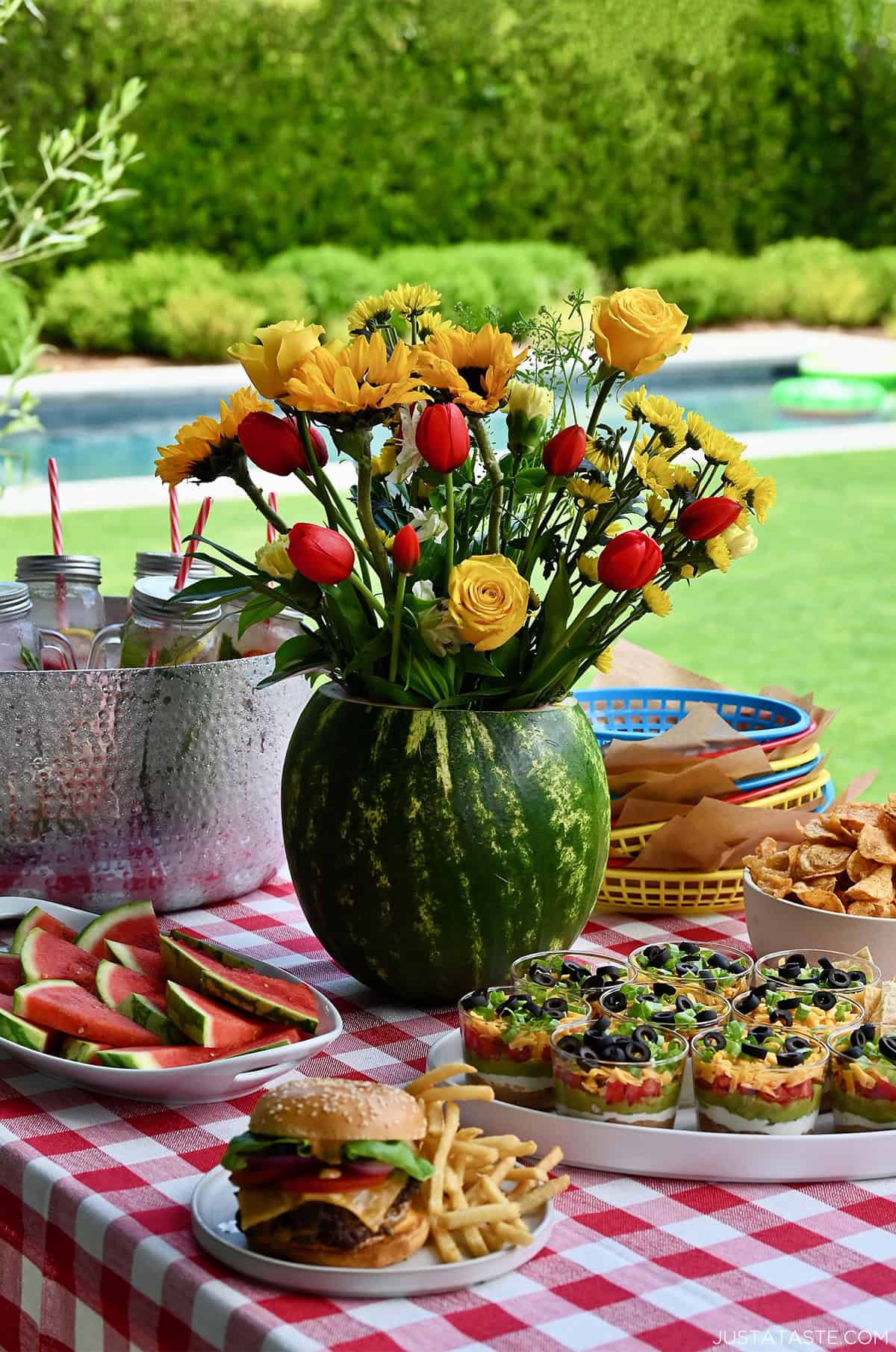 Watermelon centerpiece on a table lined with a red and white-checkered tablecloth.