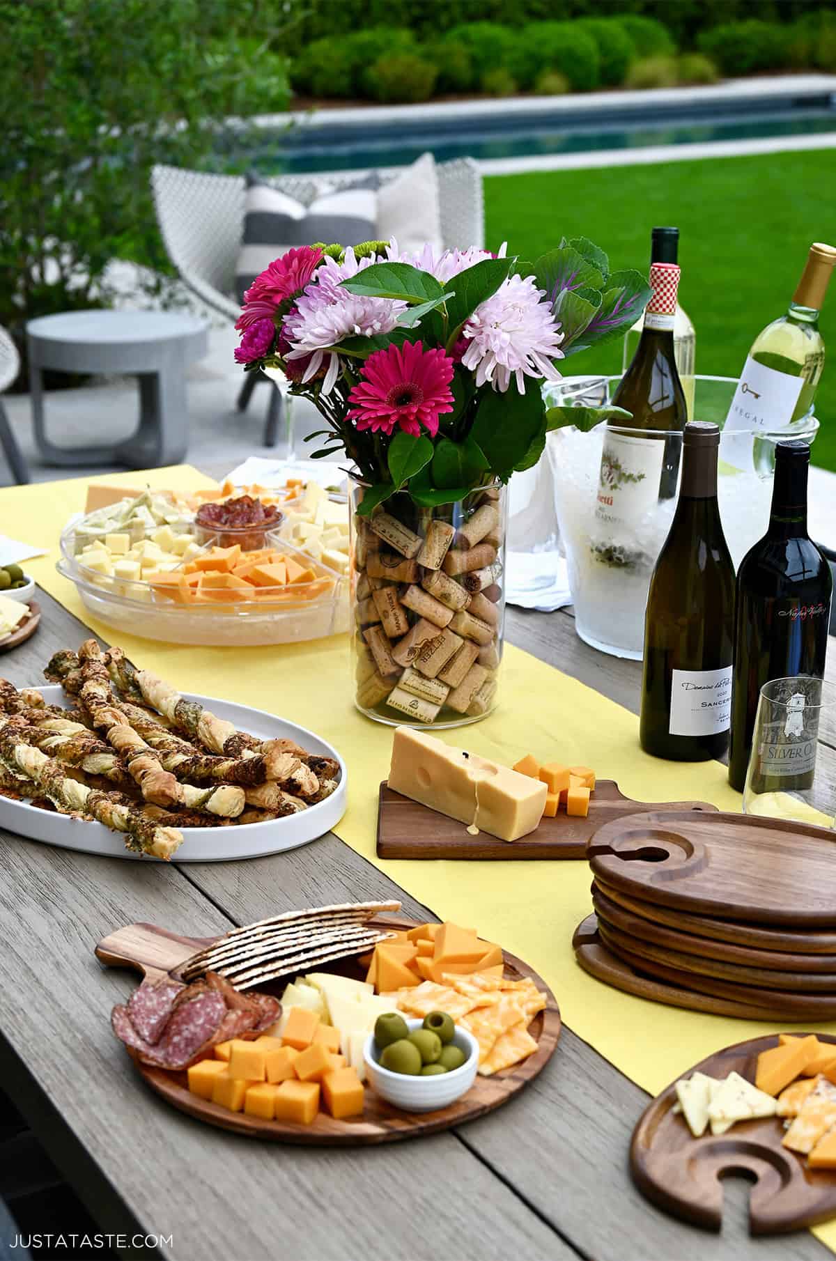 An outdoor table set with wine and cheese for hosting a small party with friends and family.