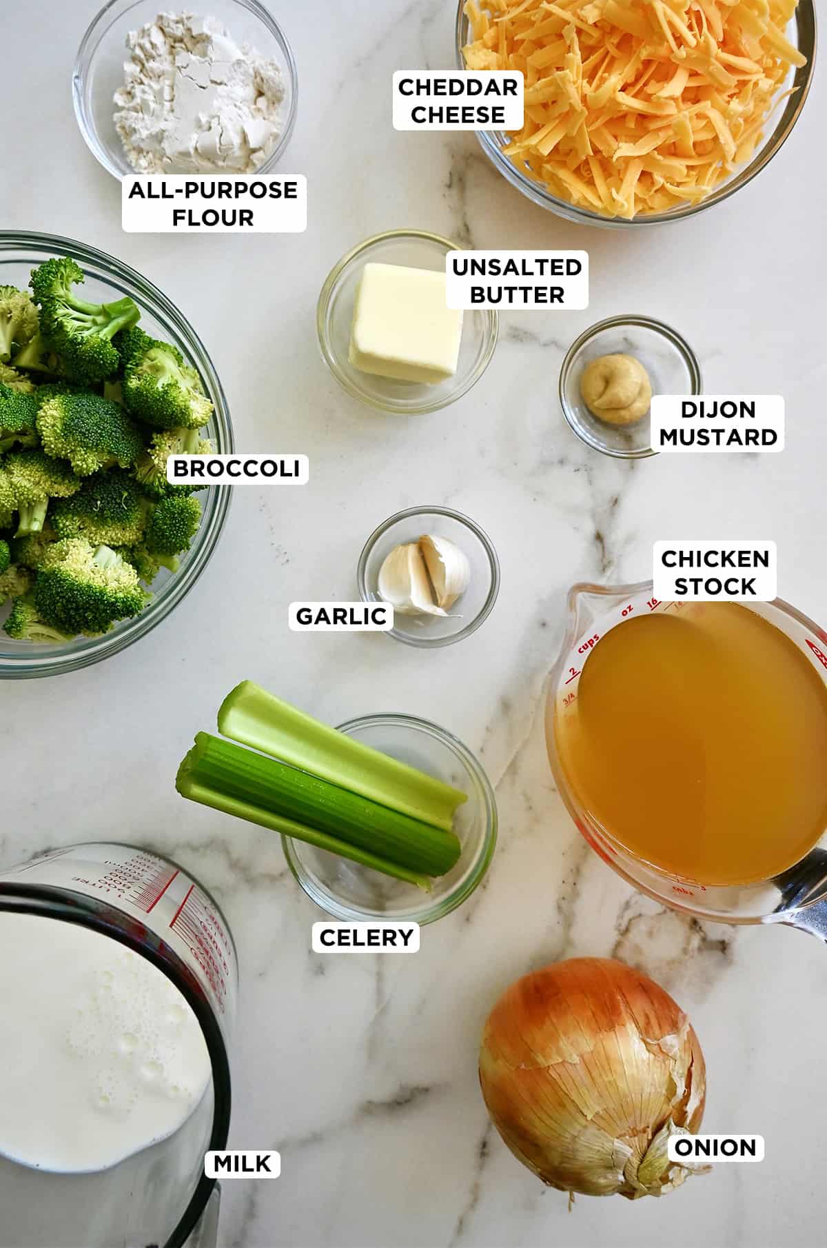 All the ingredients to make homemade broccoli cheddar soup are in various sizes of glass bowls.