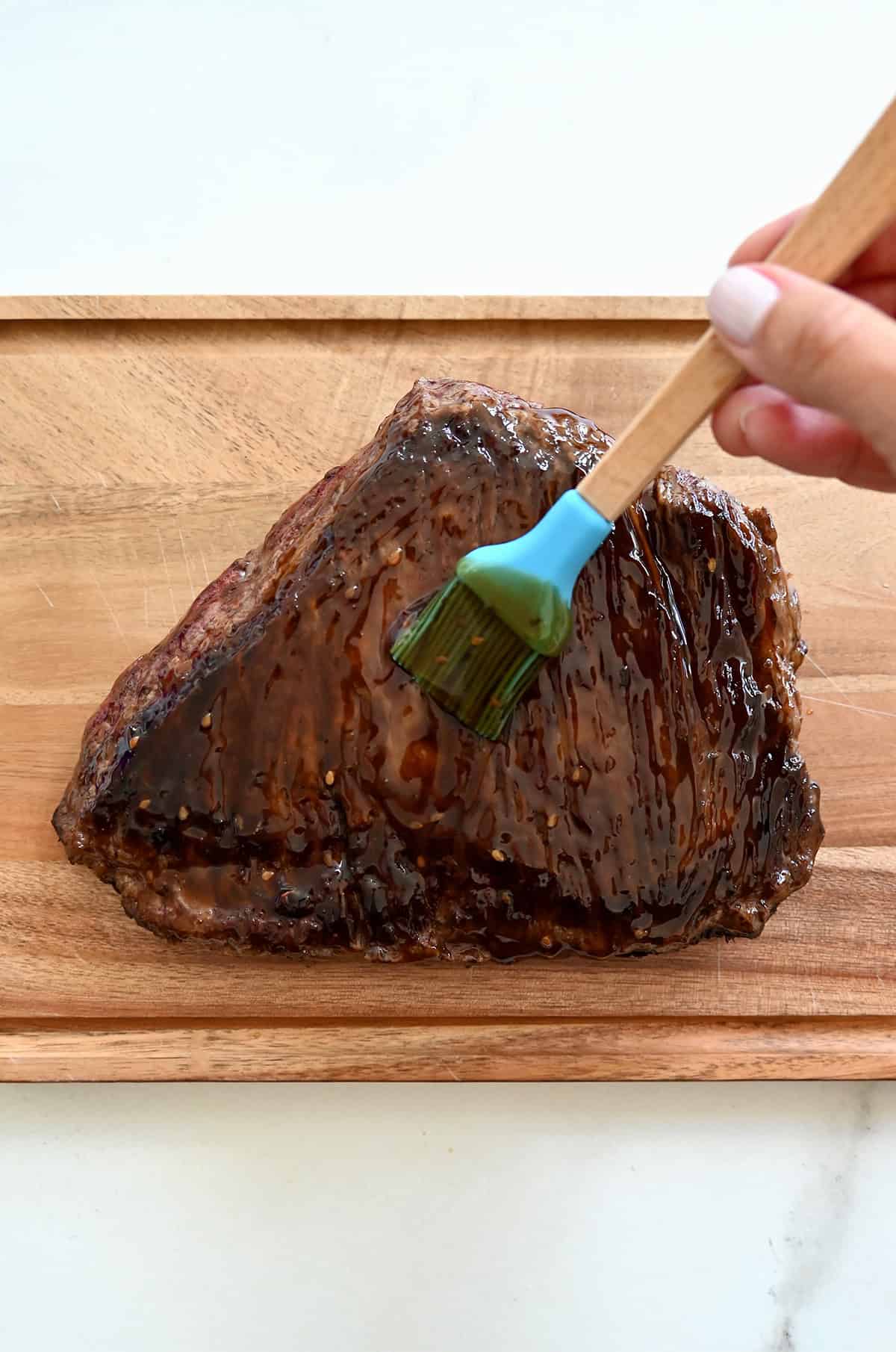 Brushing seared steak with teriyaki sauce.