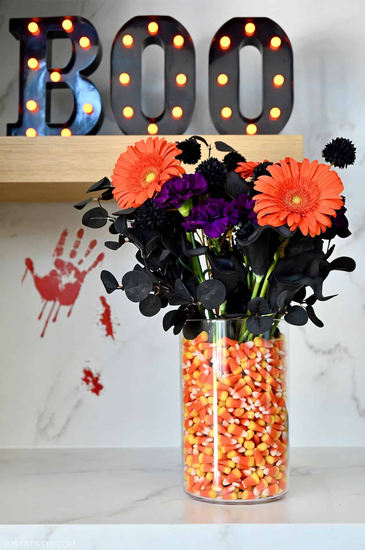 A candy corn vase with a black and orange floral arrangement.