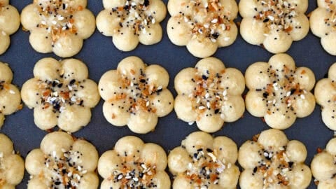 Golden Southern cheese crackers (savory spritz cookies) pressed into flower shapes and sprinkled with everything seasoning.