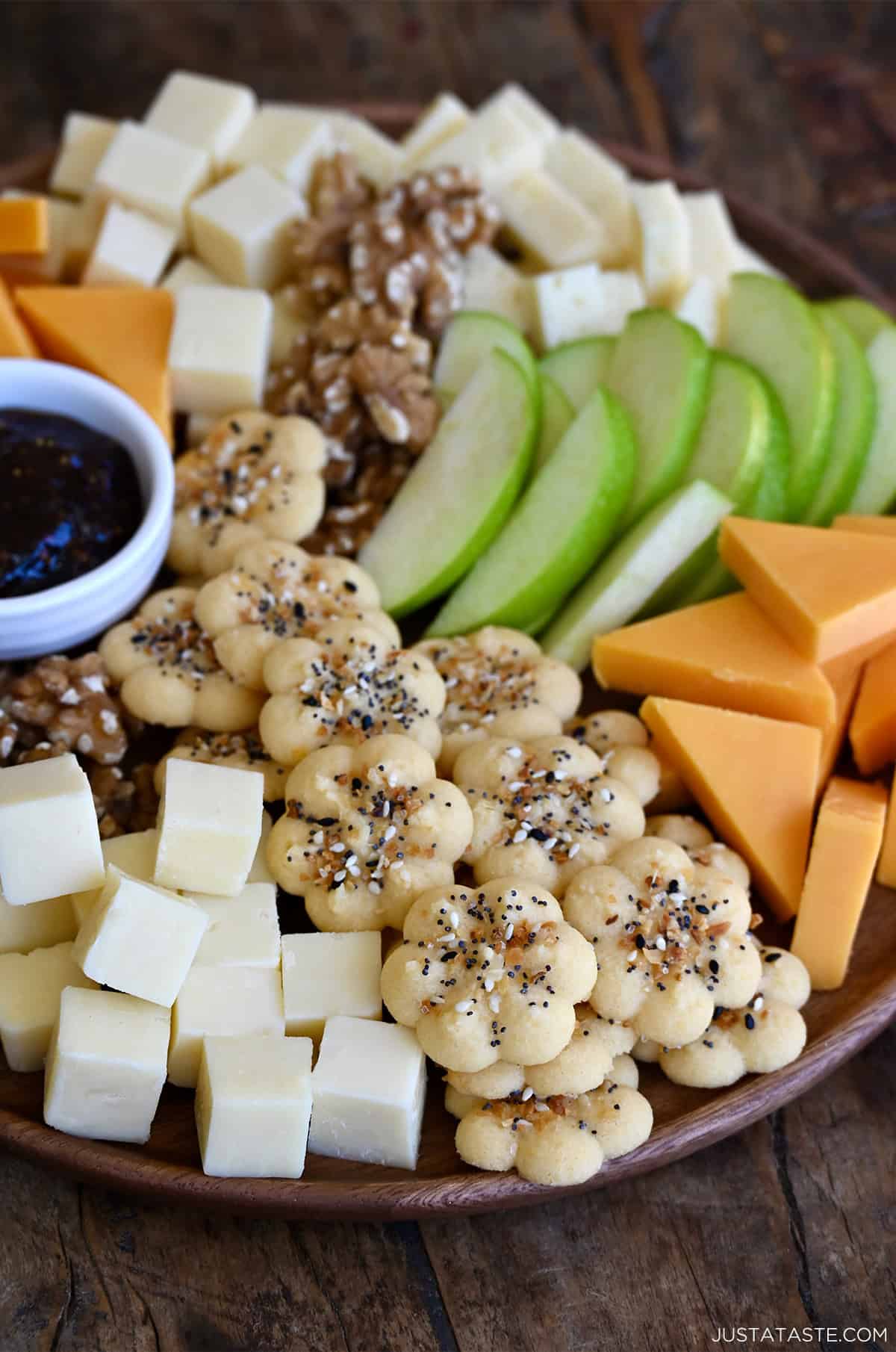Homemade Southern Cheese Crackers sprinkled with everything bagel seasoning, arranged on a charcuterie board with jam, cured meats, cheeses, nuts and sliced apple.