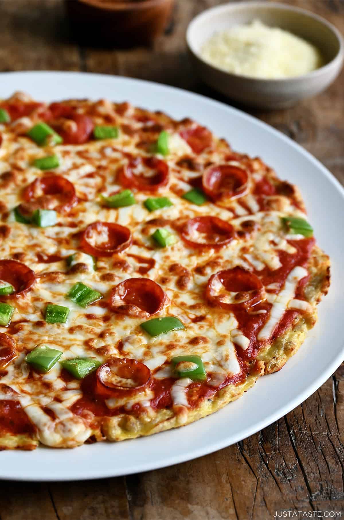 A pizza with a chicken crust topped with melty mozzarella, diced green peppers and pepperoni.