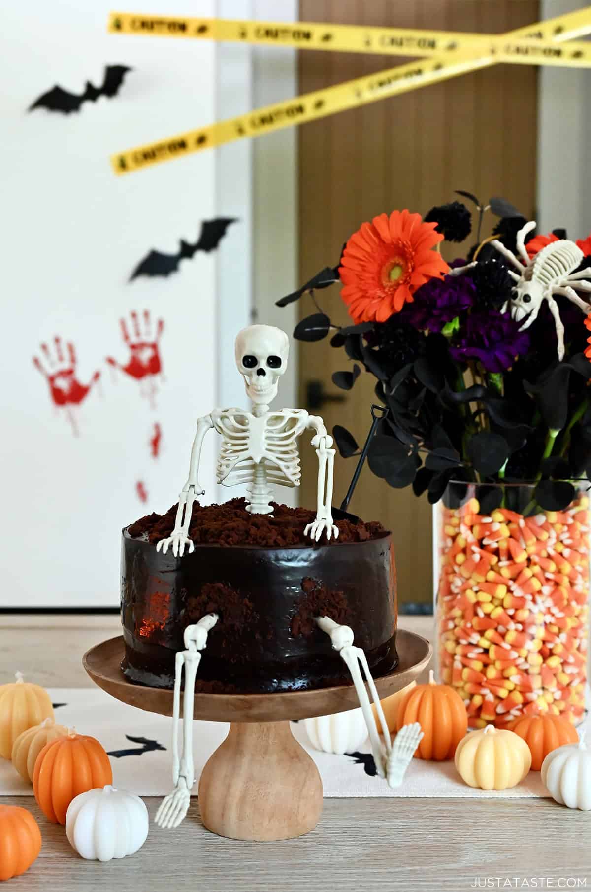 Halloween chocolate cake with a skeleton topper on a cake stand.