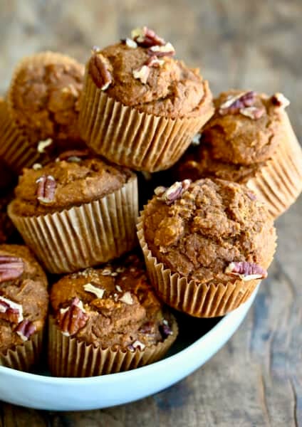 A bowl overflowing with healthy pumpkin muffins studded with pecans.