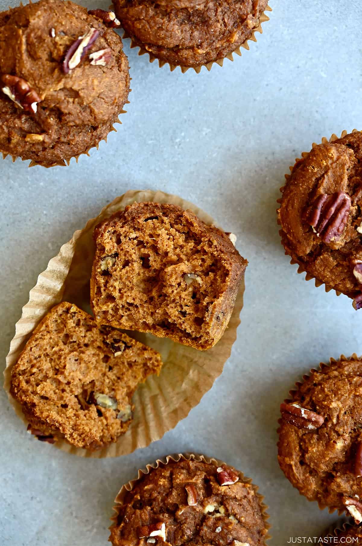 A pumpkin muffin with pecans cut in half, exposing the moist and tender center.