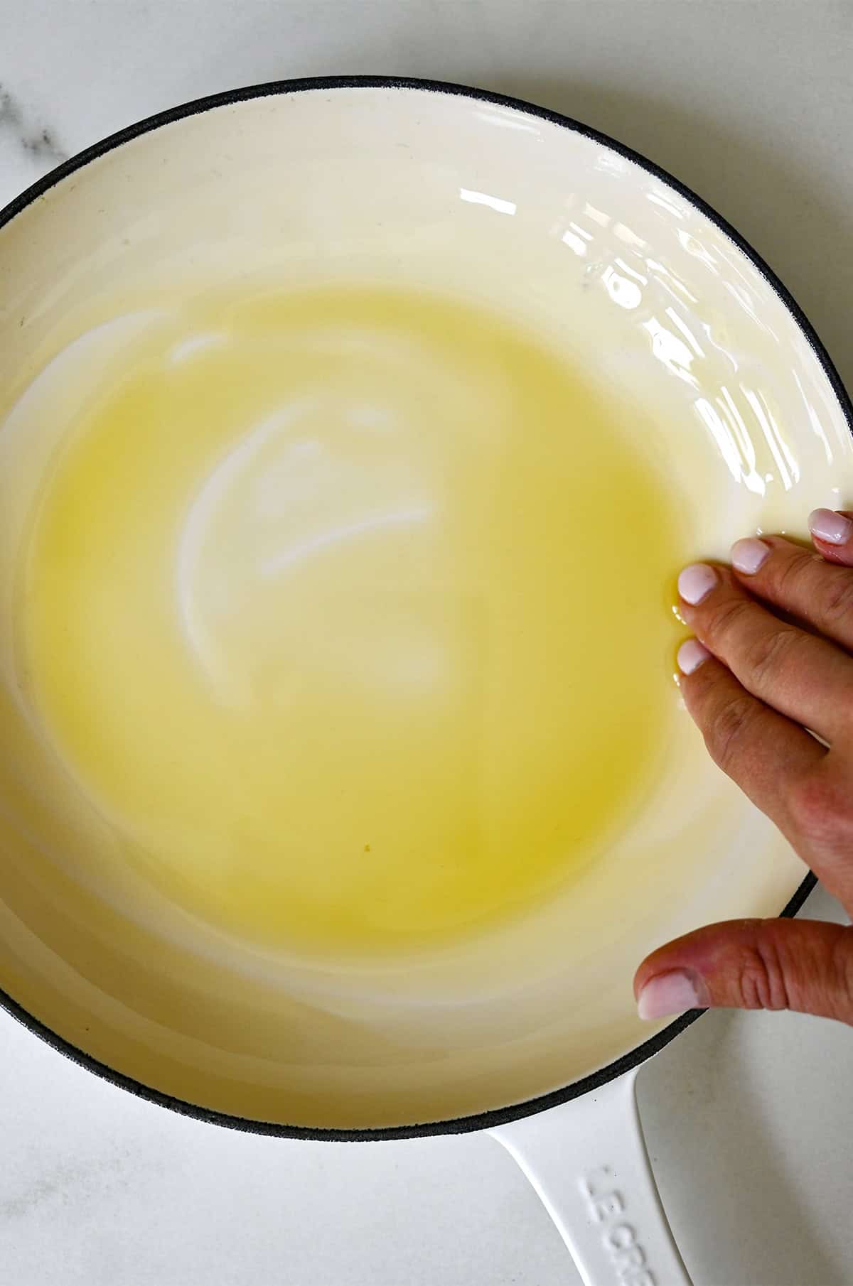 Coating the bottom and sides of a skillet with olive oil.