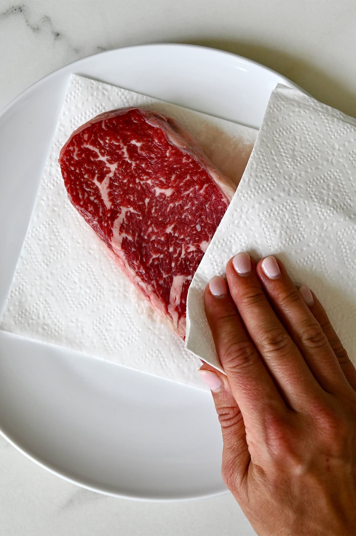 Patting a steak dry with a paper towel before pan-searing to get that perfect steakhouse crust. 