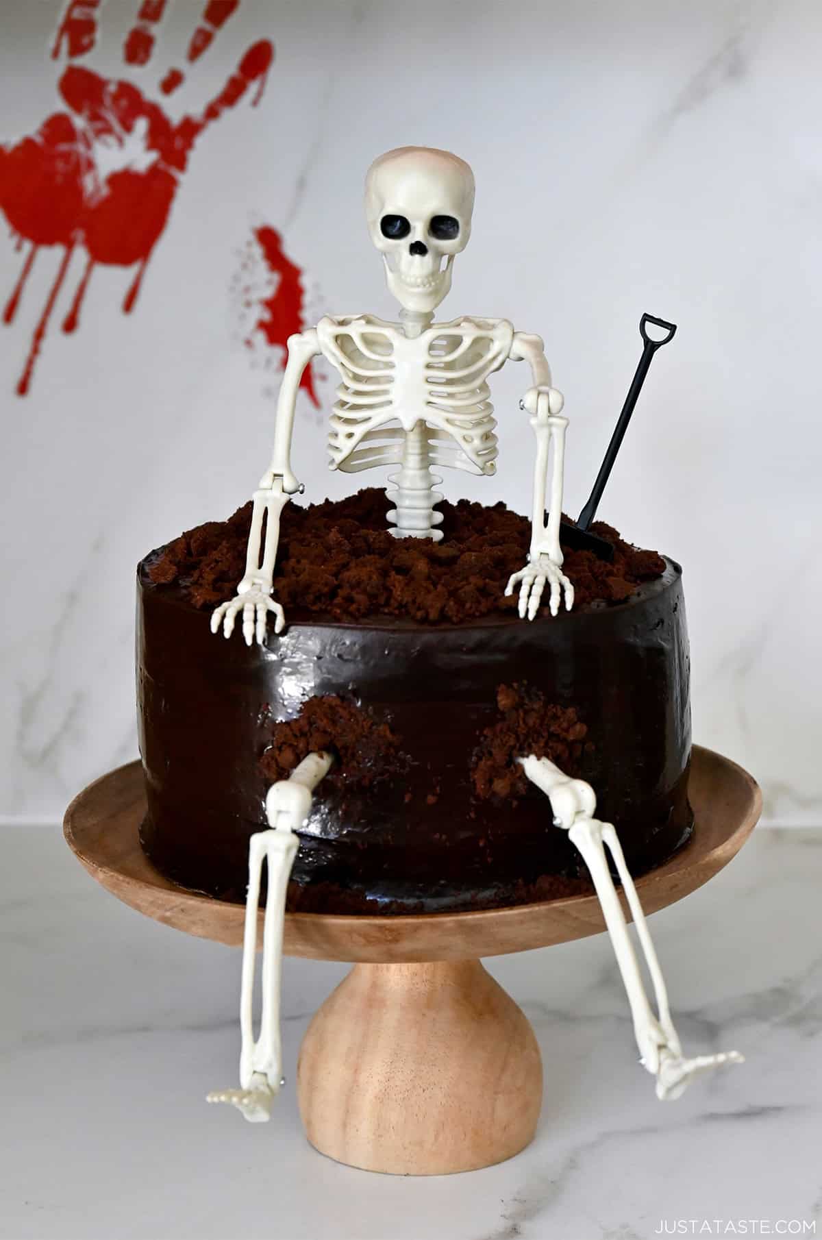 A Halloween-themed chocolate cake with chocolate frosting, complete with a plastic skeleton cake topper.