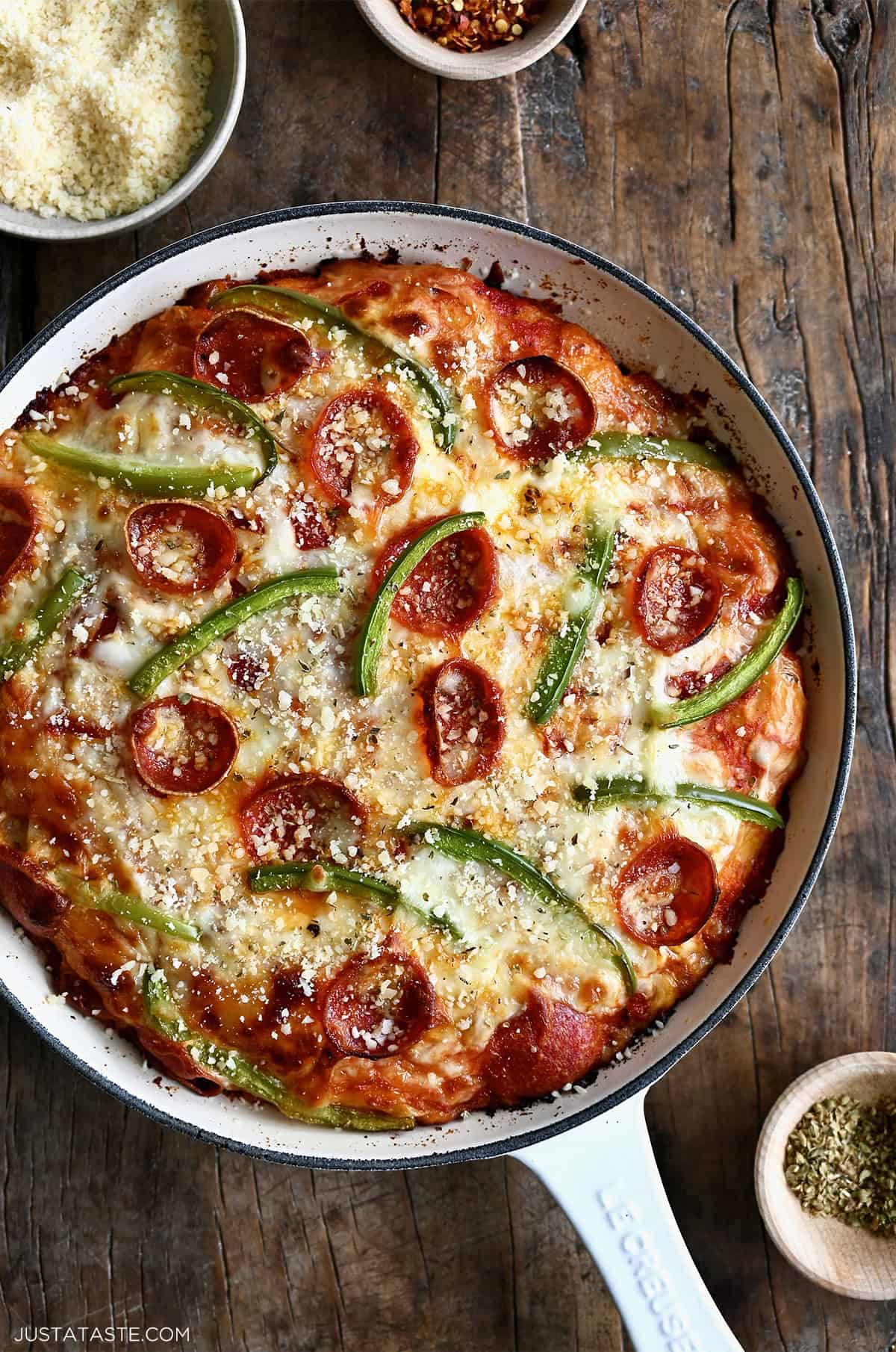 Cast iron skillet pizza topped with melted mozzarella, pepperoni slices and green peppers on a golden brown crust.