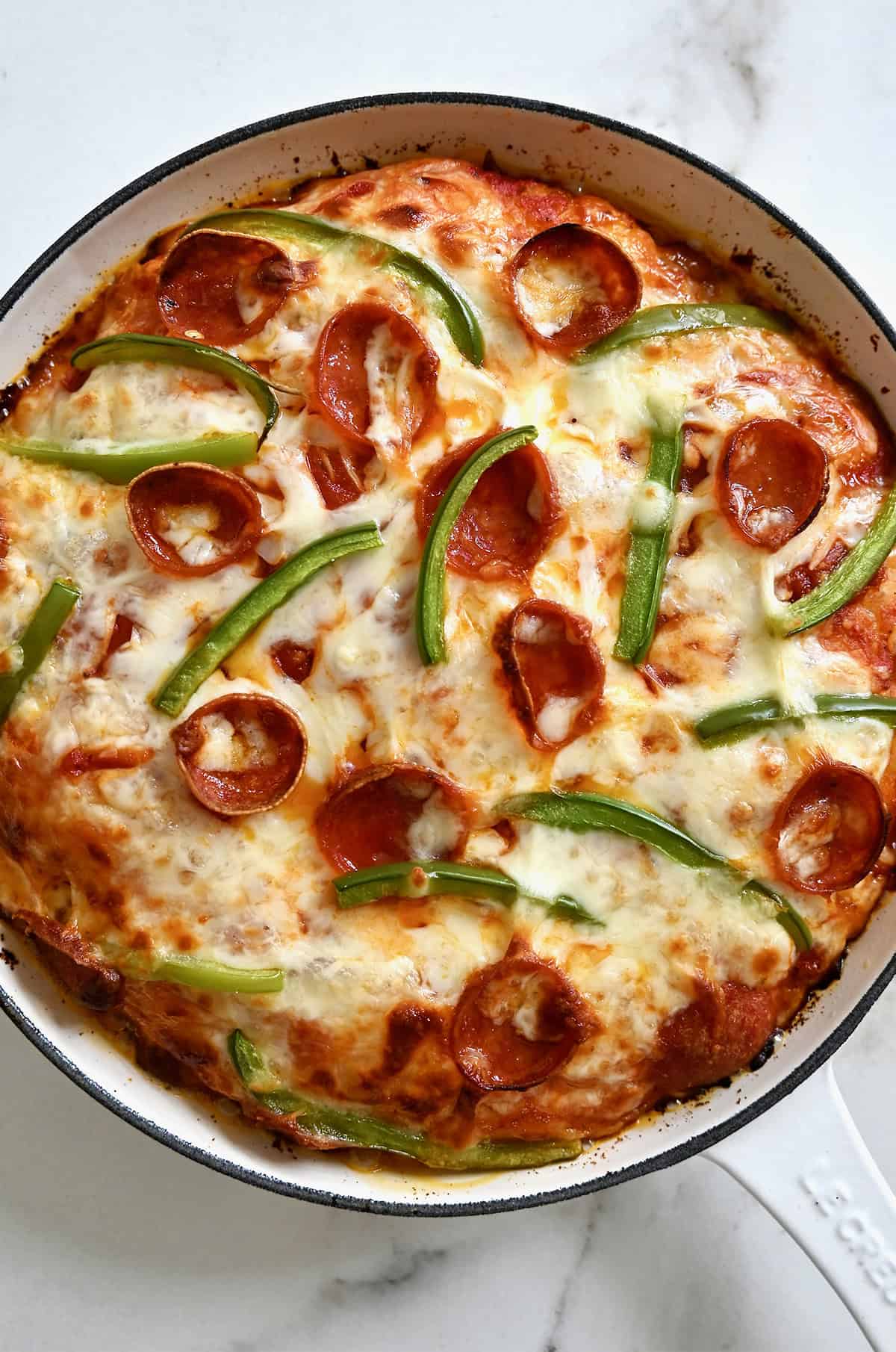 A pepperoni and green pepper skillet pizza with a crispy, golden brown crust.