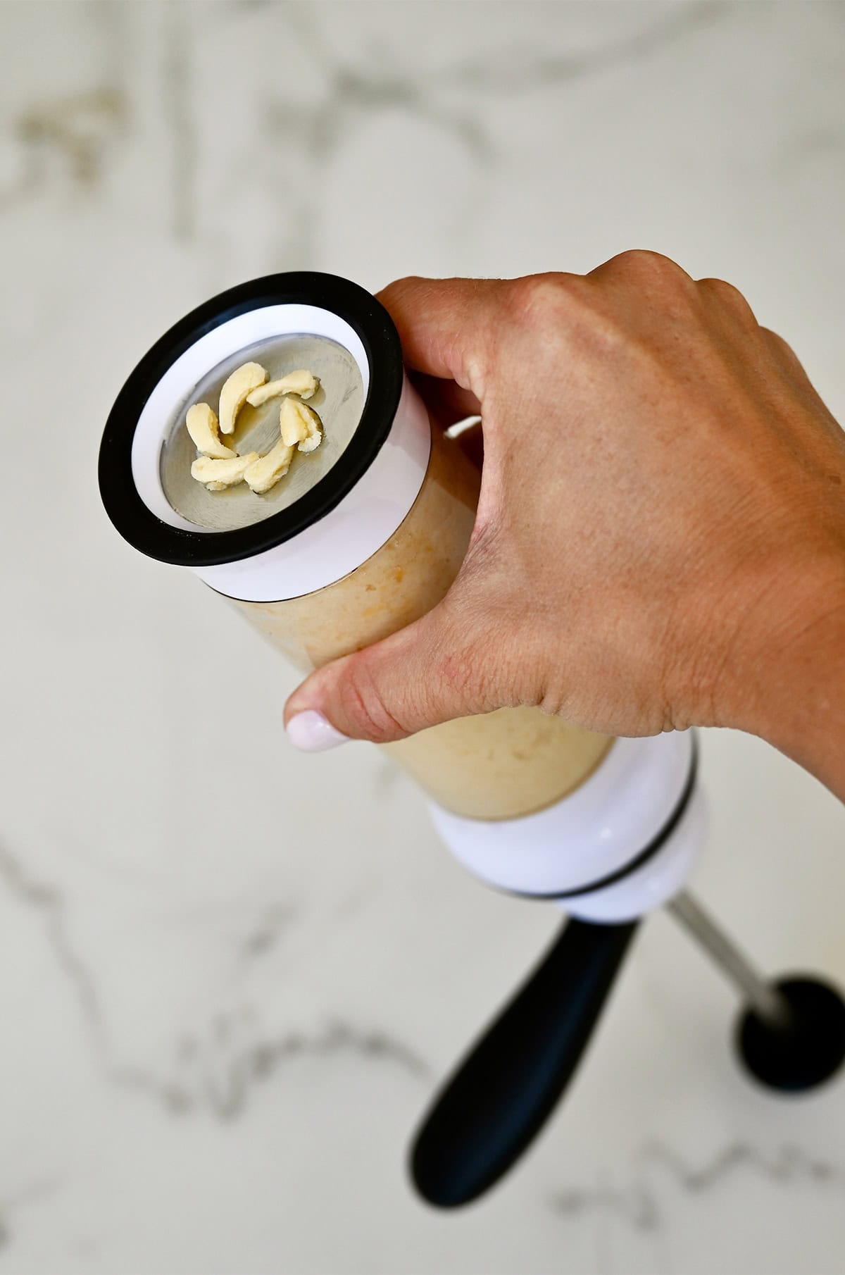 "Squirting" spritz cookie dough from a cookie press with a wreath disc.