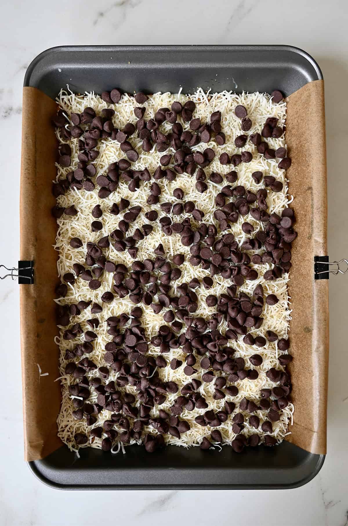Adding the chocolate chip layer of magic bars.