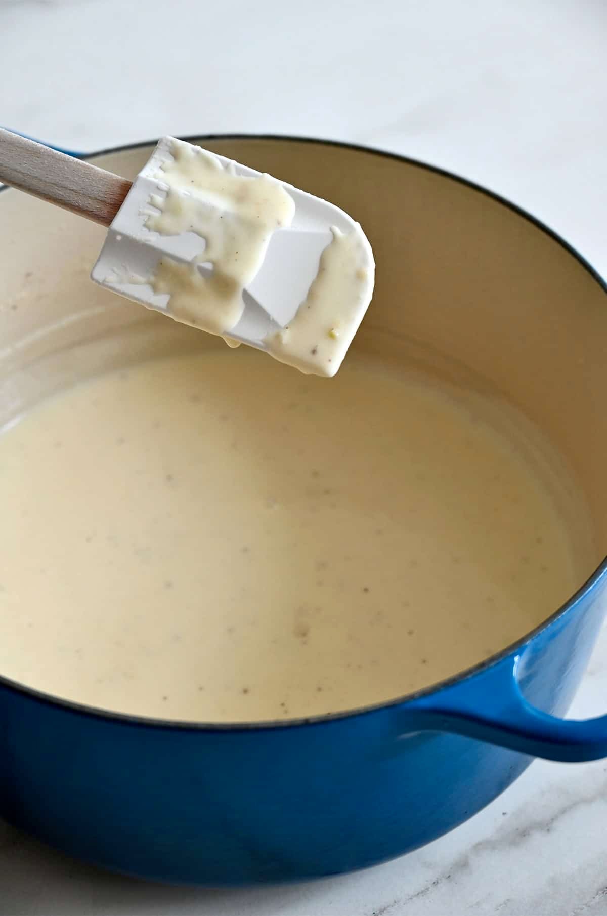 Thickened homemade Alfredo sauce coating a spatula.