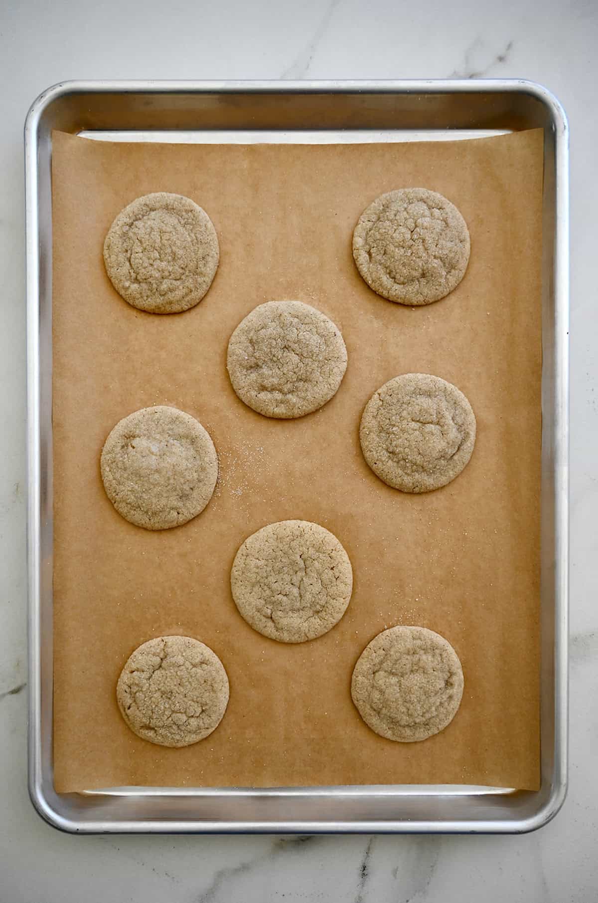 Baked chai cookies cooling on a parchment paper-lined baking sheet.