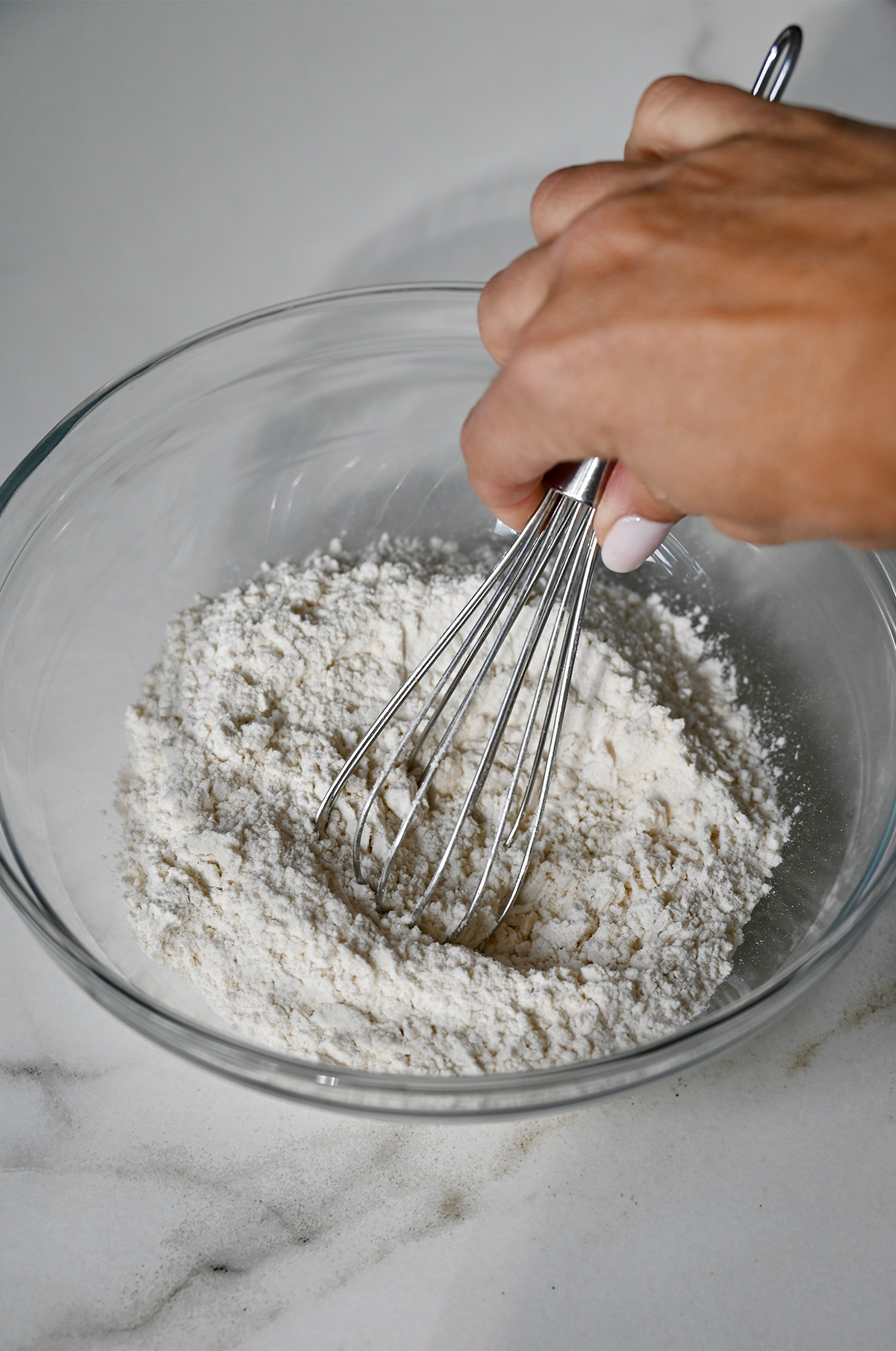 Whisking together flour, chai tea spices, baking soda and salt in a bowl.