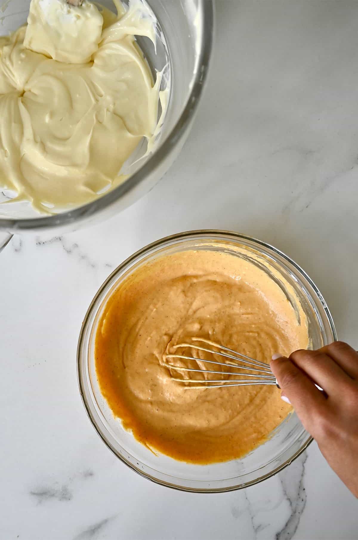 Cheesecake batter and pumpkin pie batter in glass bowls.