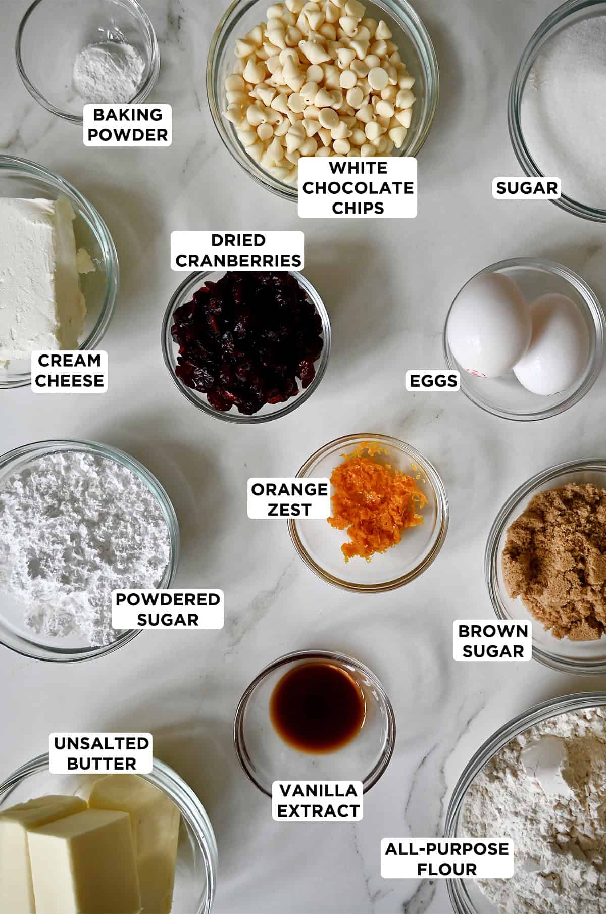 All of the ingredients needed to make cranberry bliss bars in various sizes of glass bowls.